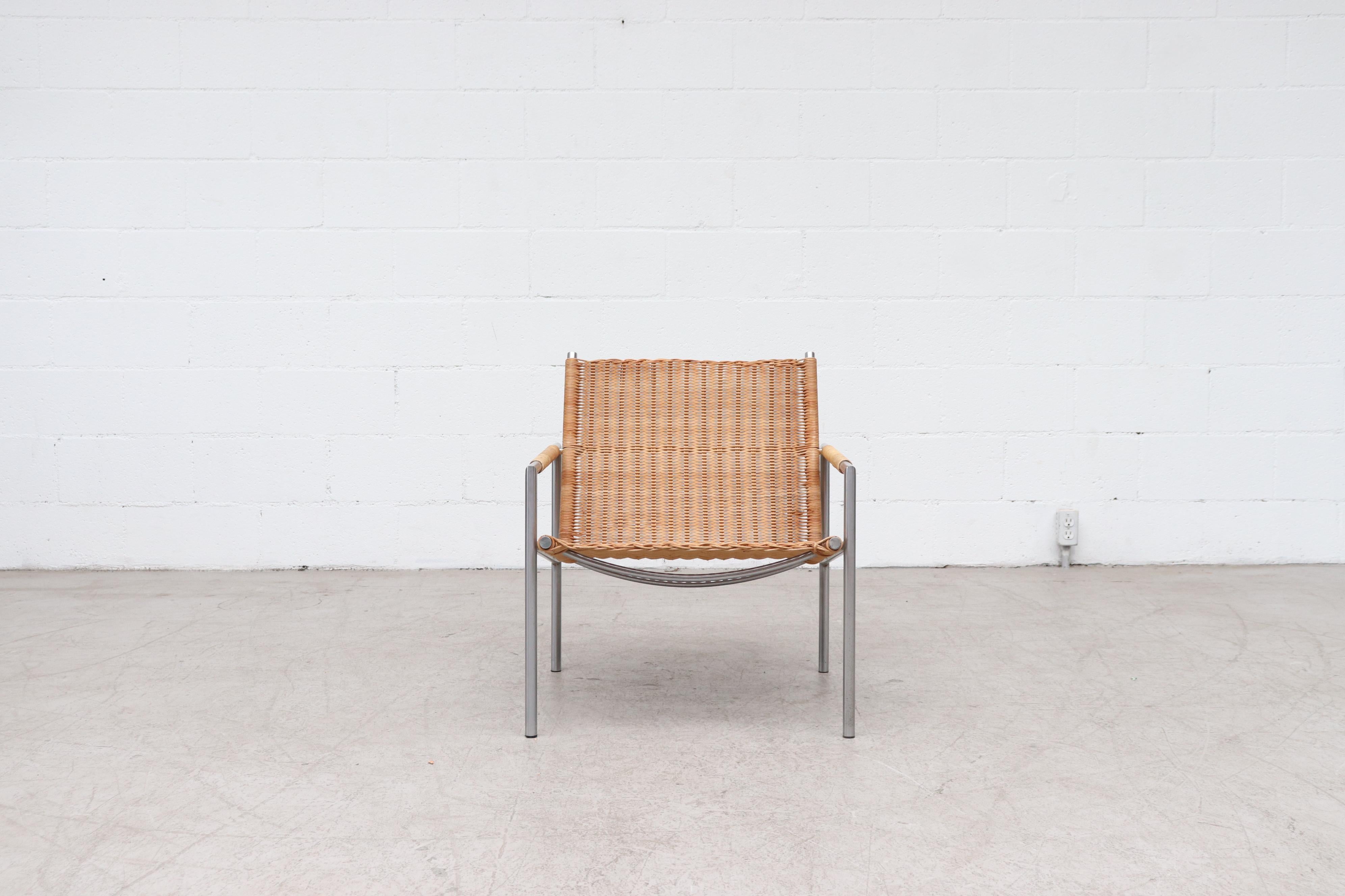 One of Martin Visser's most well-known easy chair designs of the 1960s. Architectural lounge chair with tubular chrome metal frame, Woven rattan seat and back with rattan wrap detailing on arm rests. Famed Dutch Designer Martin Visser began working