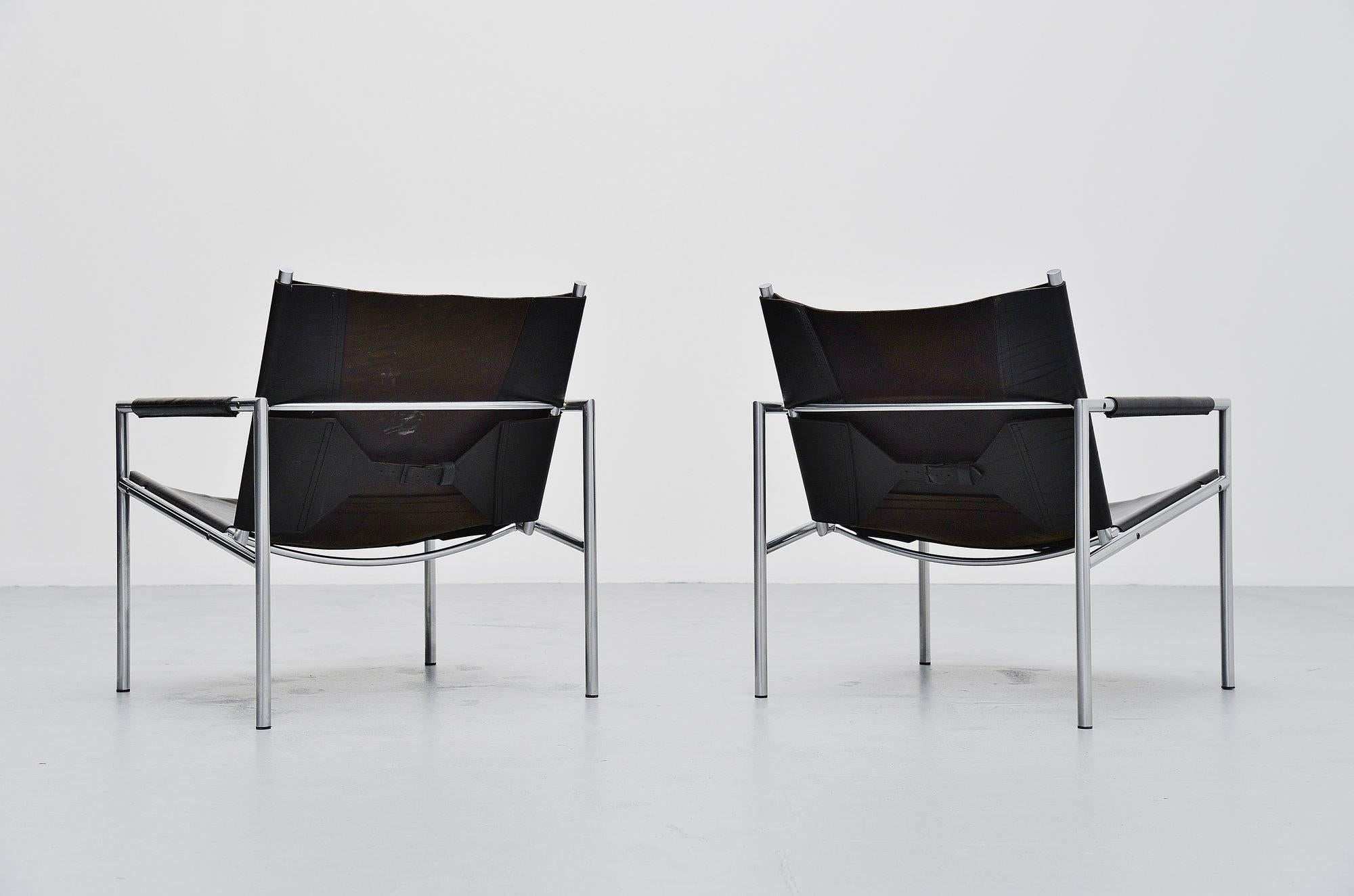 Modernist pair of lounge chairs model SZ01 designed by Martin Visser for 't Spectrum, Holland 1965. These chairs have a brushed steel tubular frame and very thick black saddle leather seats and arm rests finishing, a nice detail is the leather belt