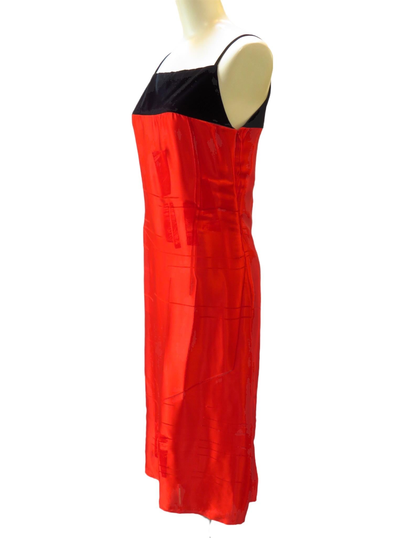 Du velours noir vient couronner cette robe en soie rouge vif de Martine Sitbon. Le tissu en soie est texturé et tombe sous le genou. Fermeture éclair latérale.
