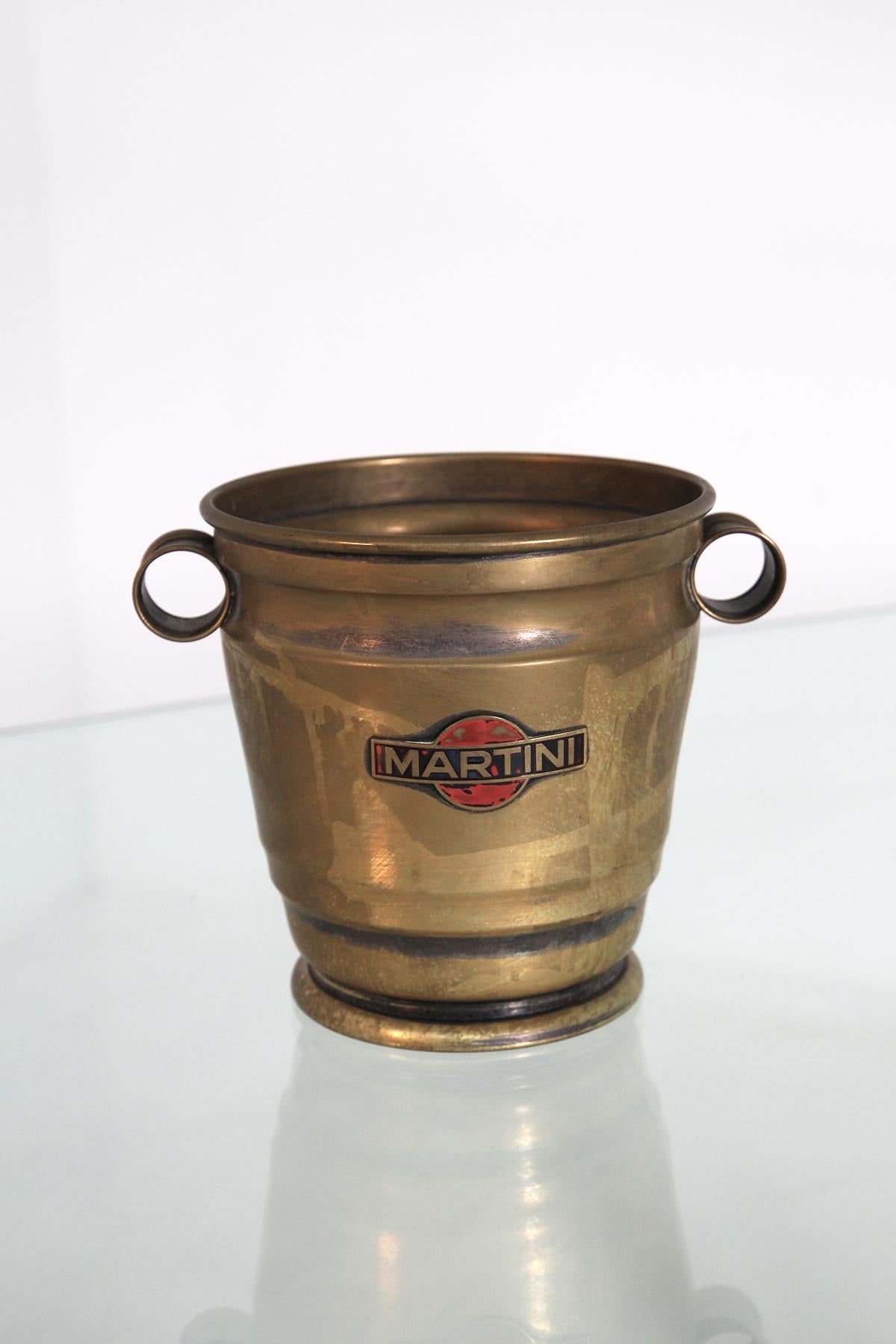 Élégant porte-glaçons italien en laiton nickelé fabriqué par Martini.
Sur le devant de la coupe de glace, on trouve leur Martini.
Aux deux extrémités, nous trouvons deux boutons pour faciliter la prise de la tasse.
La tasse présente de légères