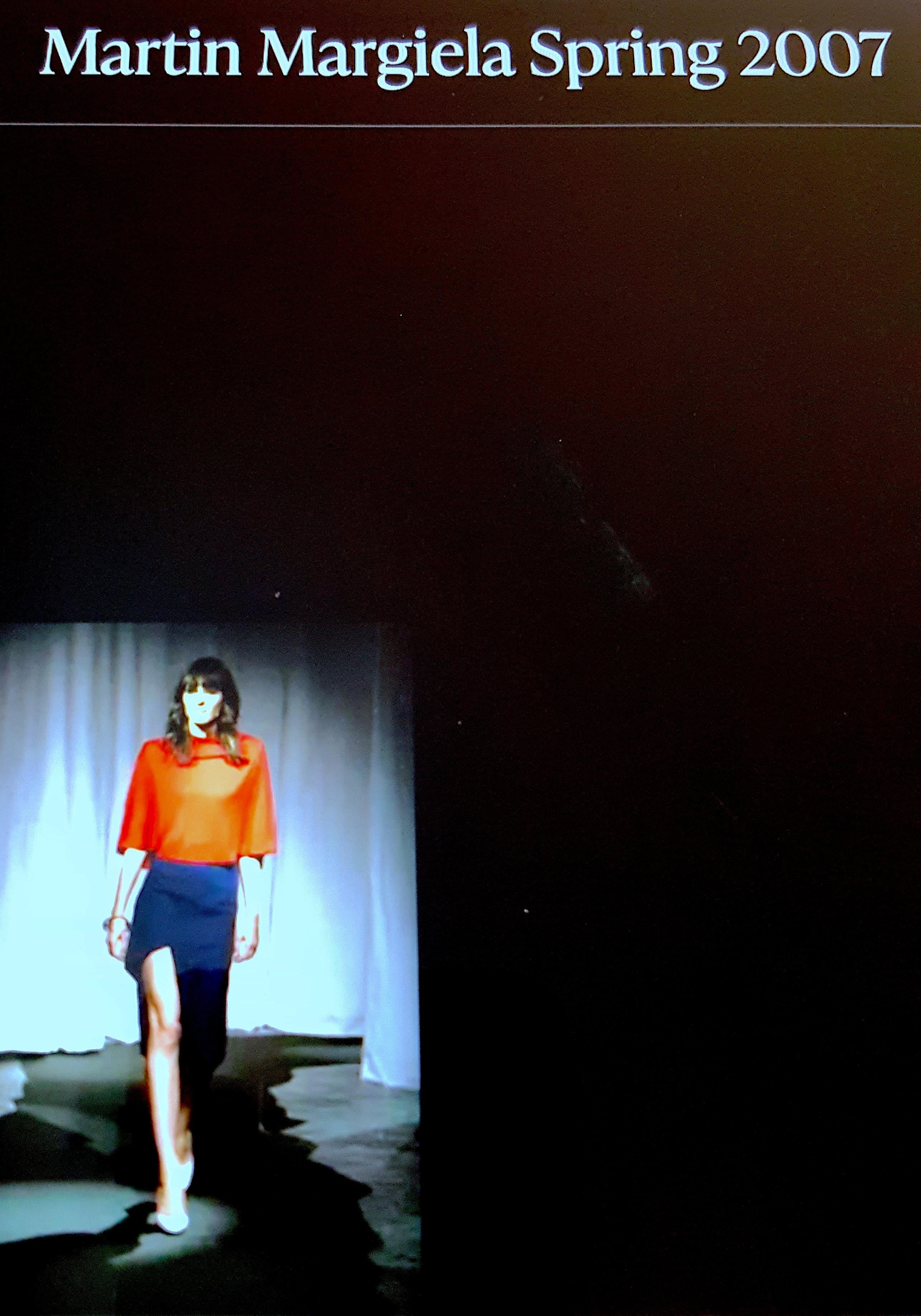 L'ex stilista belga Martin Margiela, per la sua omonima collezione Maison Martin Margiela primavera/estate 2007 dallo stile minimalista, ha fatto debuttare in passerella questa mantella corta convertibile in maglia crepe-viscosa rosso ciliegia come