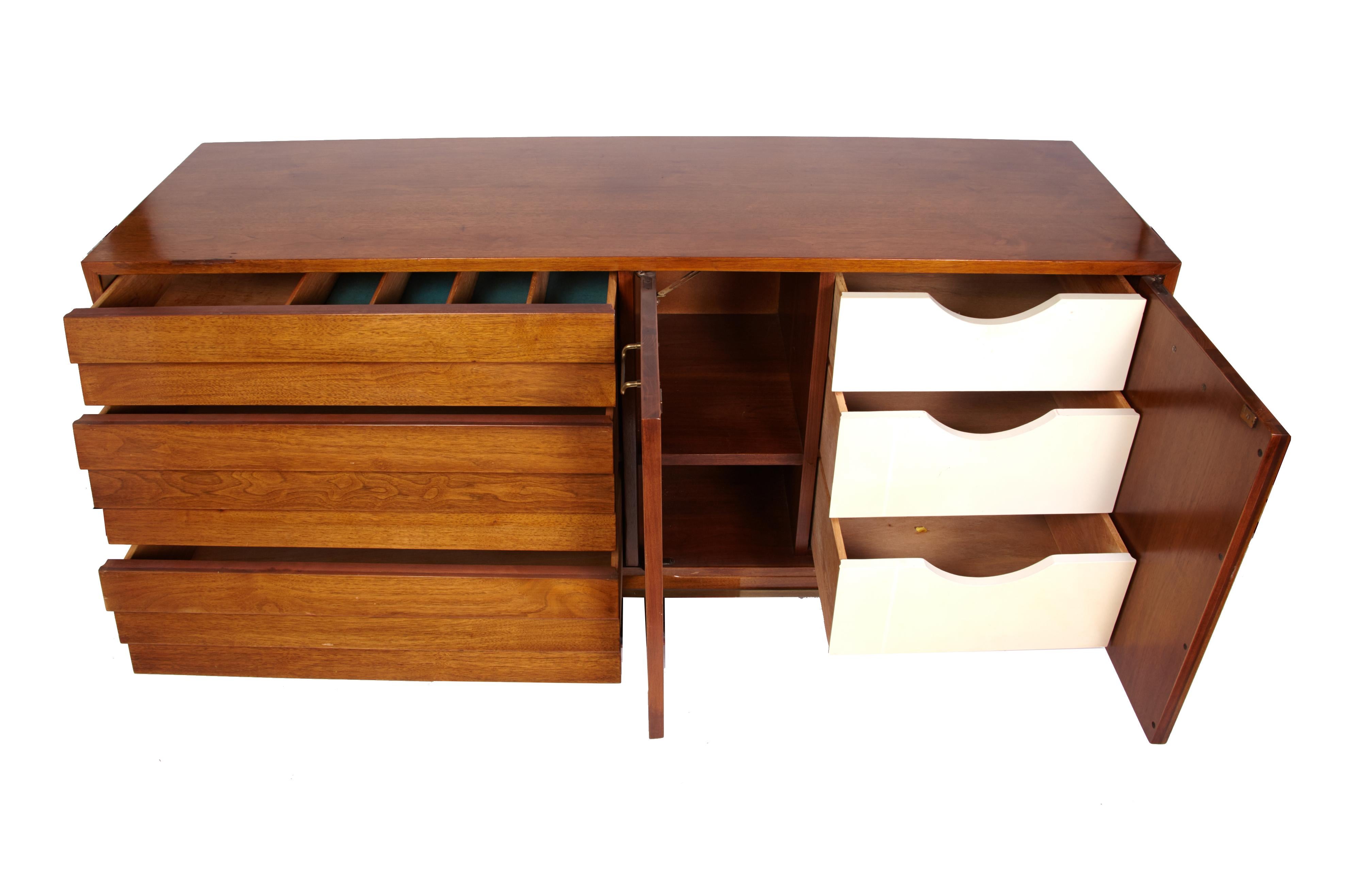 A beautiful Mid-Century Modern walnut dresser designed by Merton Gershun for American of Martinsville with louvered drawers and polished brass drawer pulls.
In excellent original condition. The doors on the right open to reveal 3 white front