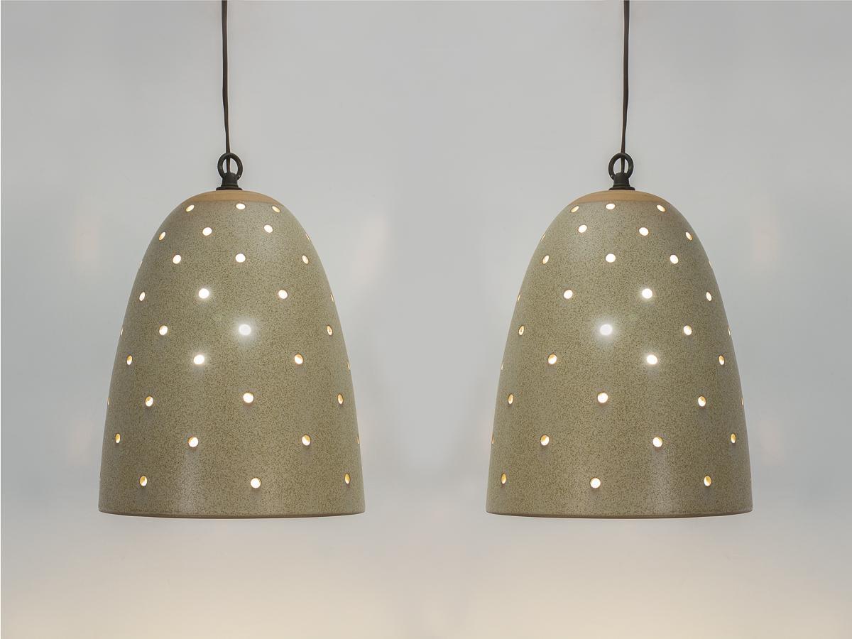 Scarce pair of perforated ceramic pendant lamps, designed by Jane and Gordon Martz for Marshall Studios. Inspired by Danish modern lighting, this handmade lamp adds warmth and texture to any interior. Conical form is finished in earthy, speckled
