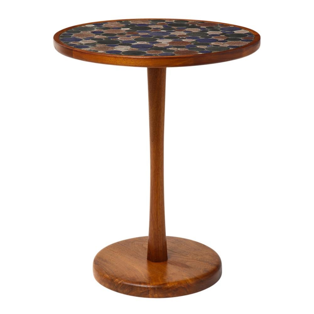 Martz side table, ceramic and walnut. Slender drink table with a 16” top of varied sized ceramic tiles, glazed in blue, moss, rust, beige and gunmetal. The walnut frame has a cast iron weighted base. The table breaks down into 3 pieces for shipping.