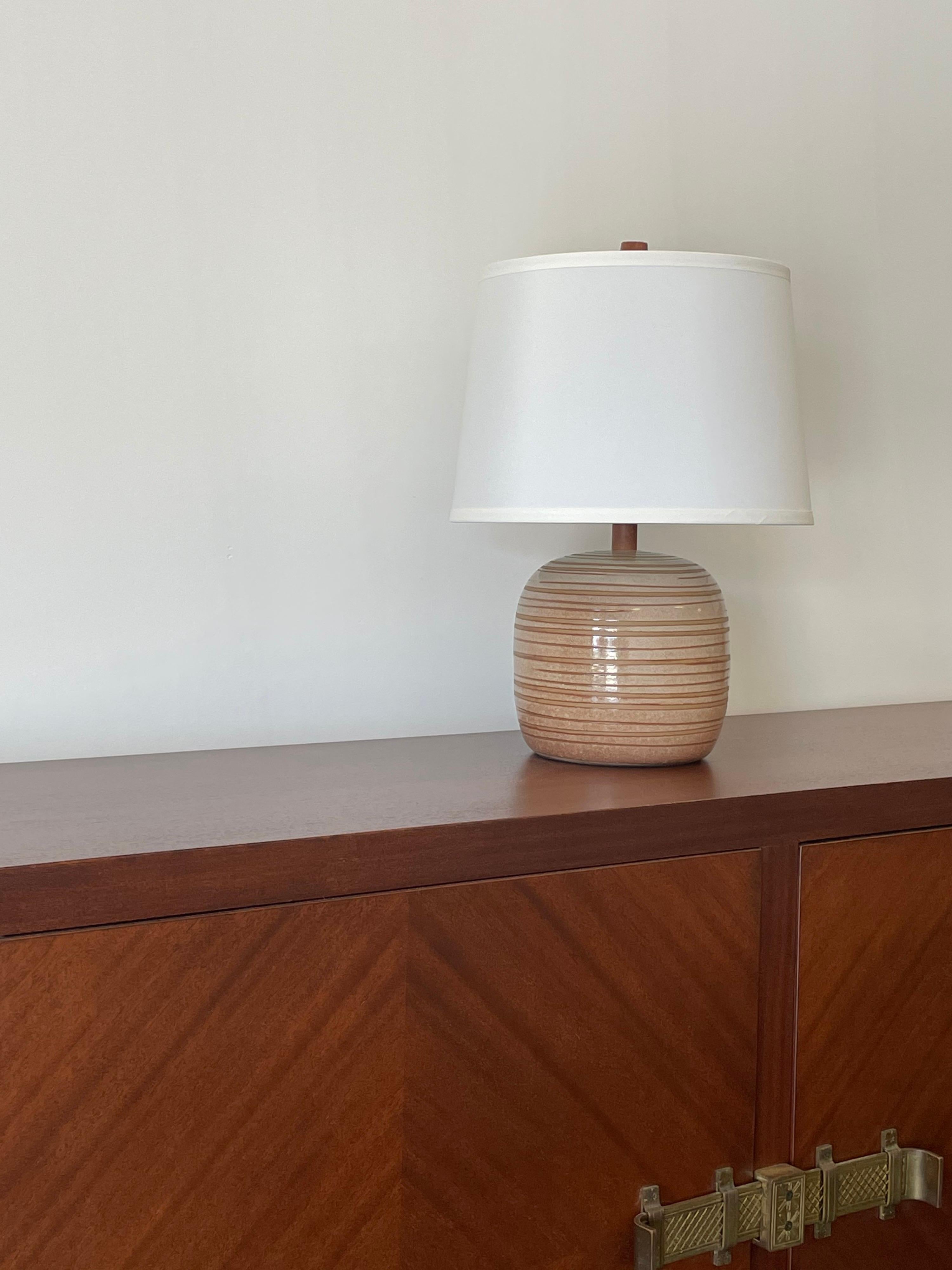 Wonderful bulbous ceramic lamp by famed ceramicist duo Jane and Gordon Martz for Marshall Studios. Features a tan and dusty rose/ blush color.
 
Measures: Overall
18.5” tall
13” wide

Ceramic only 
7.5” tall
7.5” wide.

Shade is shown for