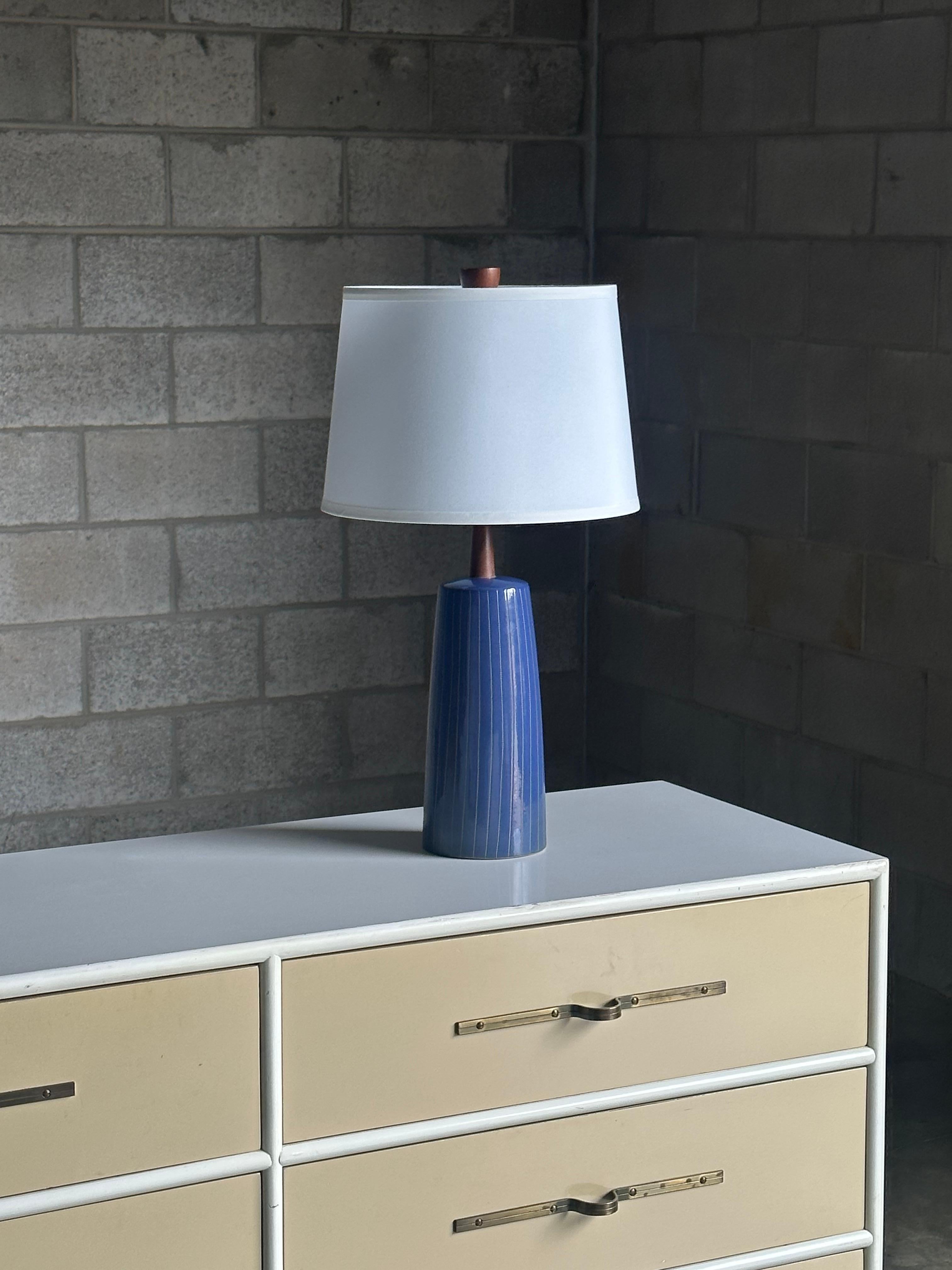 A wonderful table lamp designed by famed ceramicist duo Jane and Gordon Martz for Marshall Studios. Features a royal blue glaze with incised vertical stripes. Great walnut finial to complete the lamp.

Overall dimensions:
24” tall
13” wide

Ceramic
