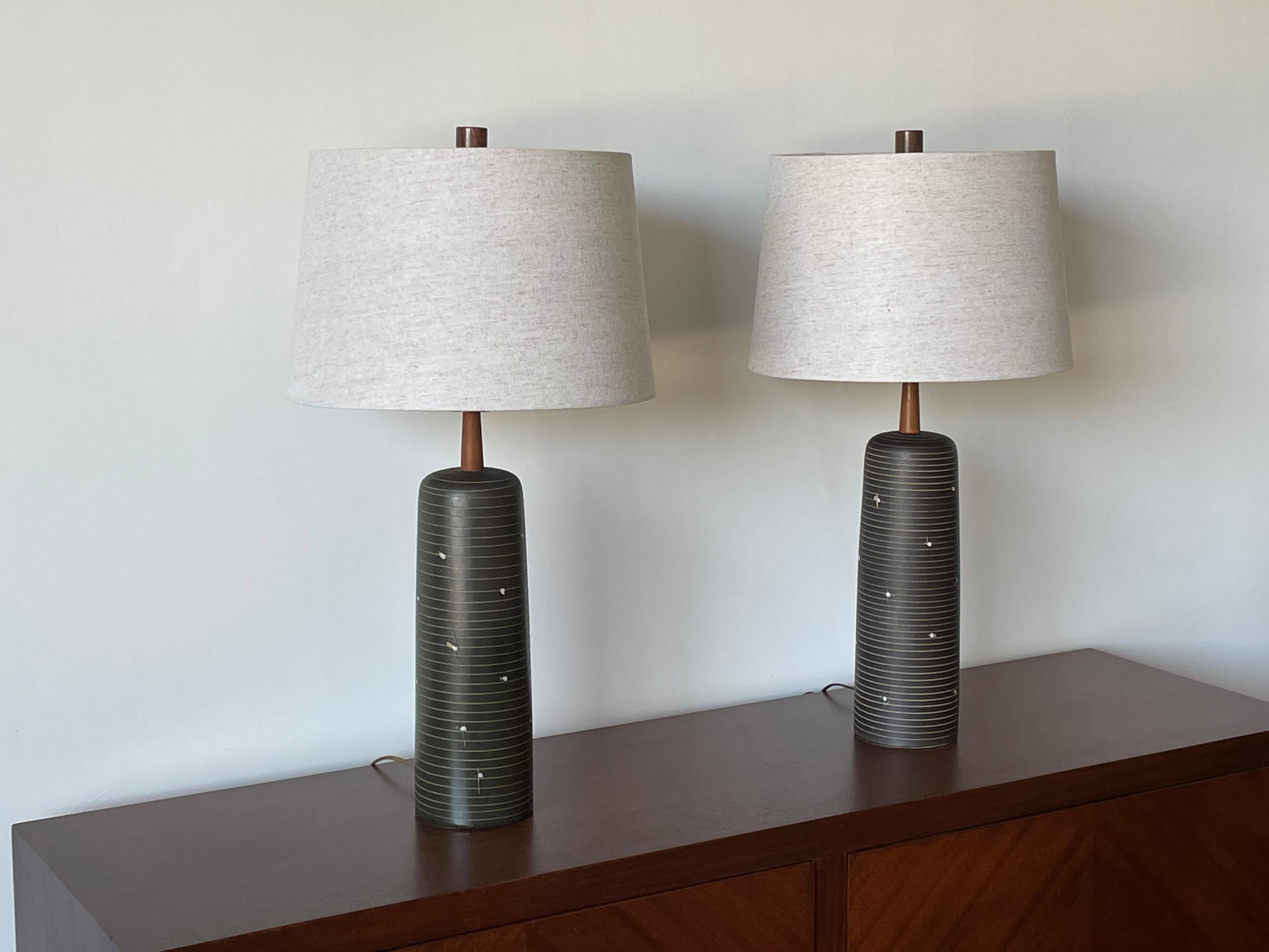 A pair of elegant lamps by famed ceramicist duo Jane and Gordon Martz for Marshall Studios. Features a black matte glaze with incised swirl and detail. Please note that lamps are not an exact match. There is a very slightly color and glaze