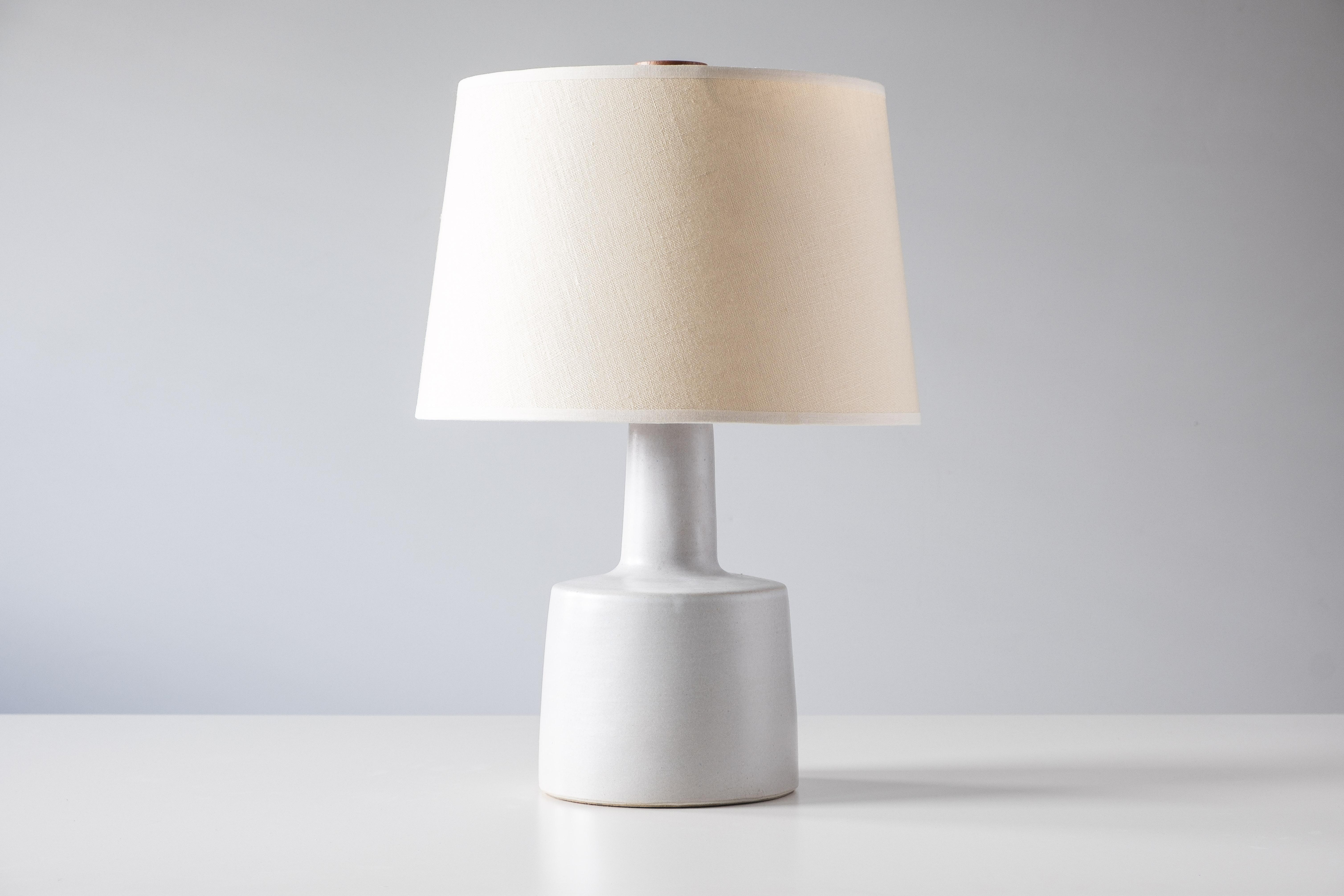 What is it?
—
Another gem from the masters of mid century lightning – Gordon and Jane Martz.

This signed Martz model 105 lamp comes in a semi-gloss white glaze with small flecks of red and blue. The lamp shows a small bit of texture from the clay
