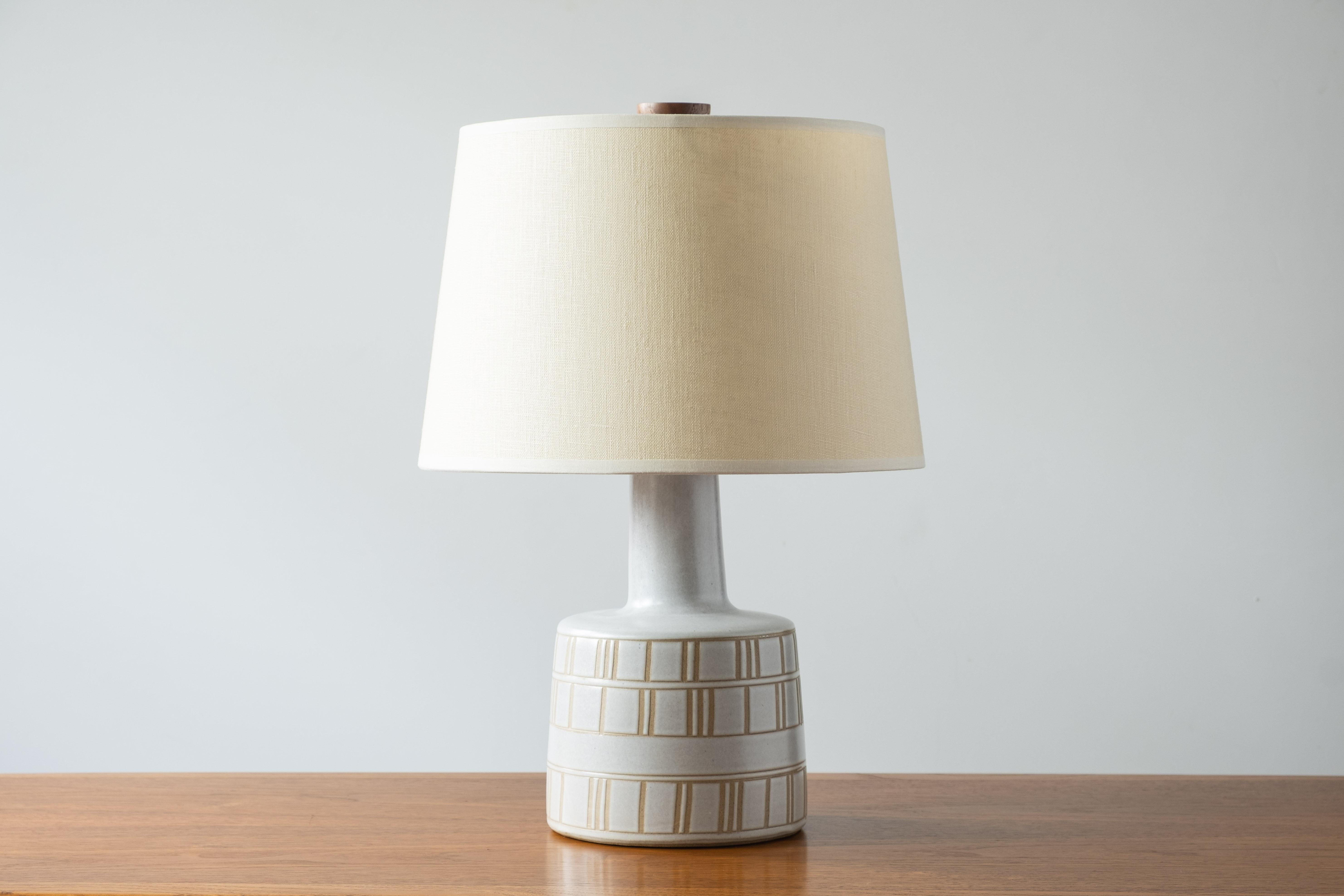 What is it?
—
Another gem from the masters of mid century lightning – Gordon and Jane Martz.

This signed Martz model 105 lamp comes in a matte white glaze with incised lines in a horizontal rectangle pattern. The glaze is not a pure bright white,