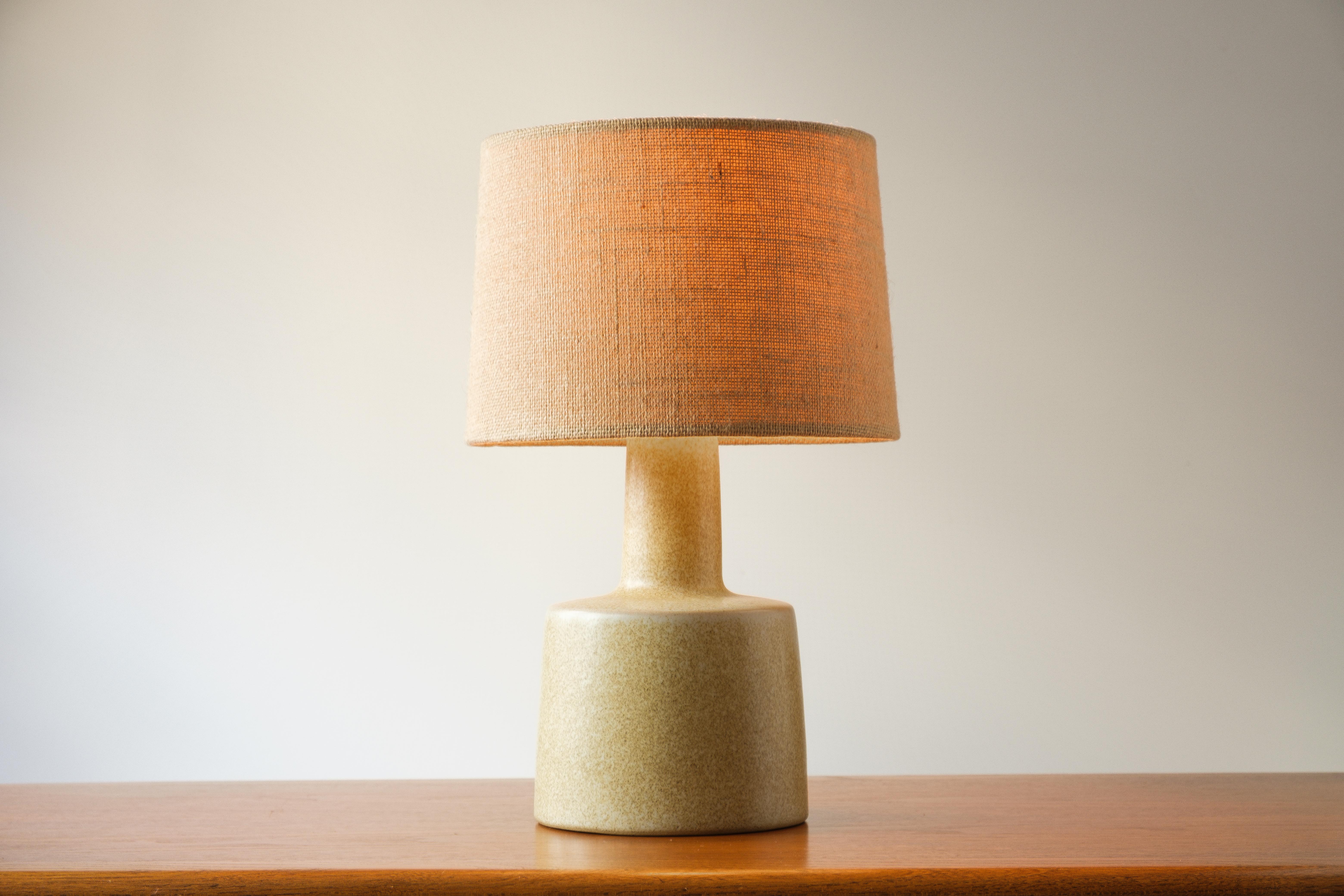 What is it?
—
Another gem from the masters of mid century lightning – Gordon and Jane Martz.

This signed Martz model 105 lamp comes in a matte tan glaze with embedded textured sand. The flow of the glaze makes the sand texture thicker and