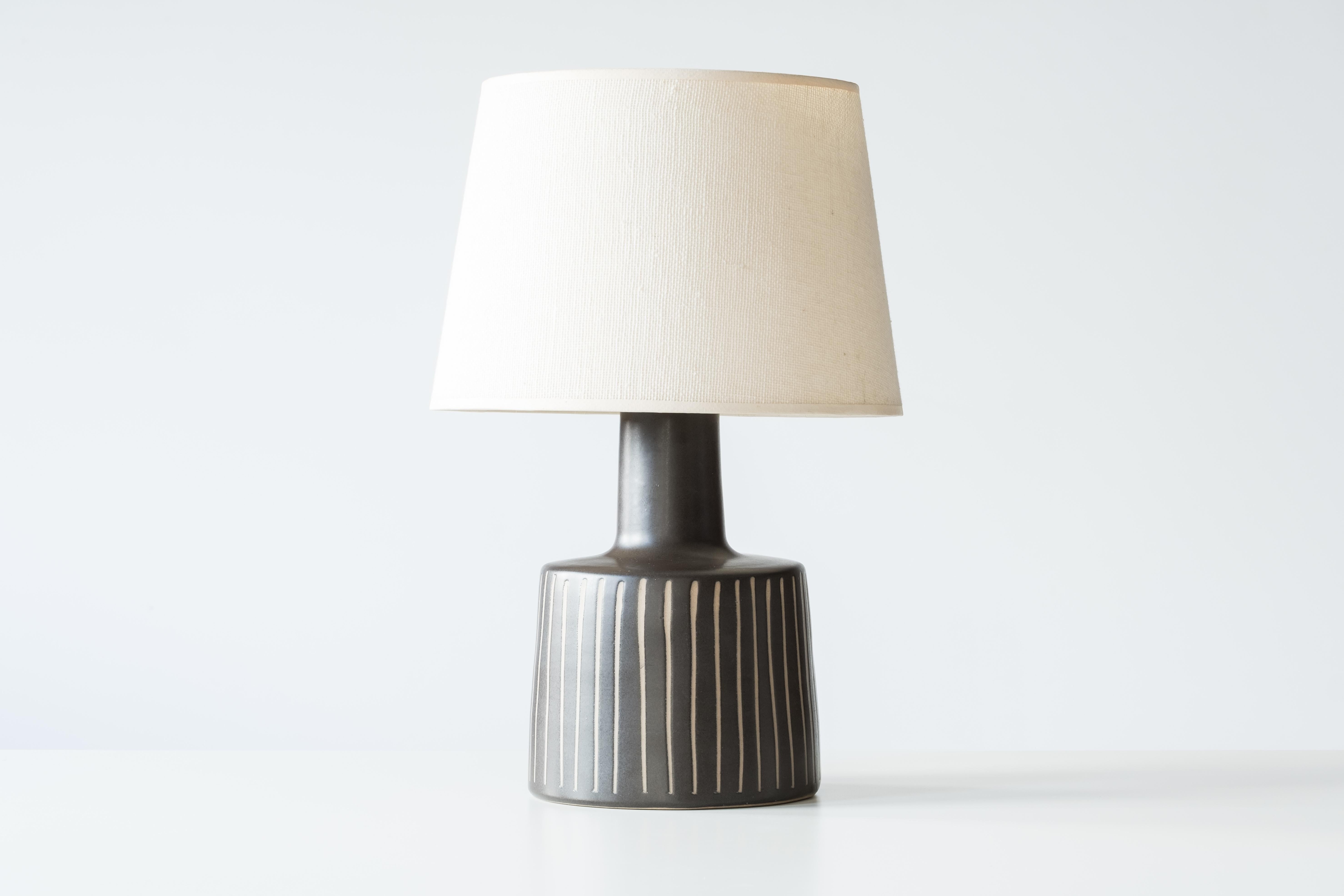 What is it?
—
Another gem from the masters of midcentury lightning – Gordon and Jane Martz.

This signed Martz model 105 lamp comes in a matte black / very dark brown glaze with a vertical stripe incised design. Technically this glaze is the
