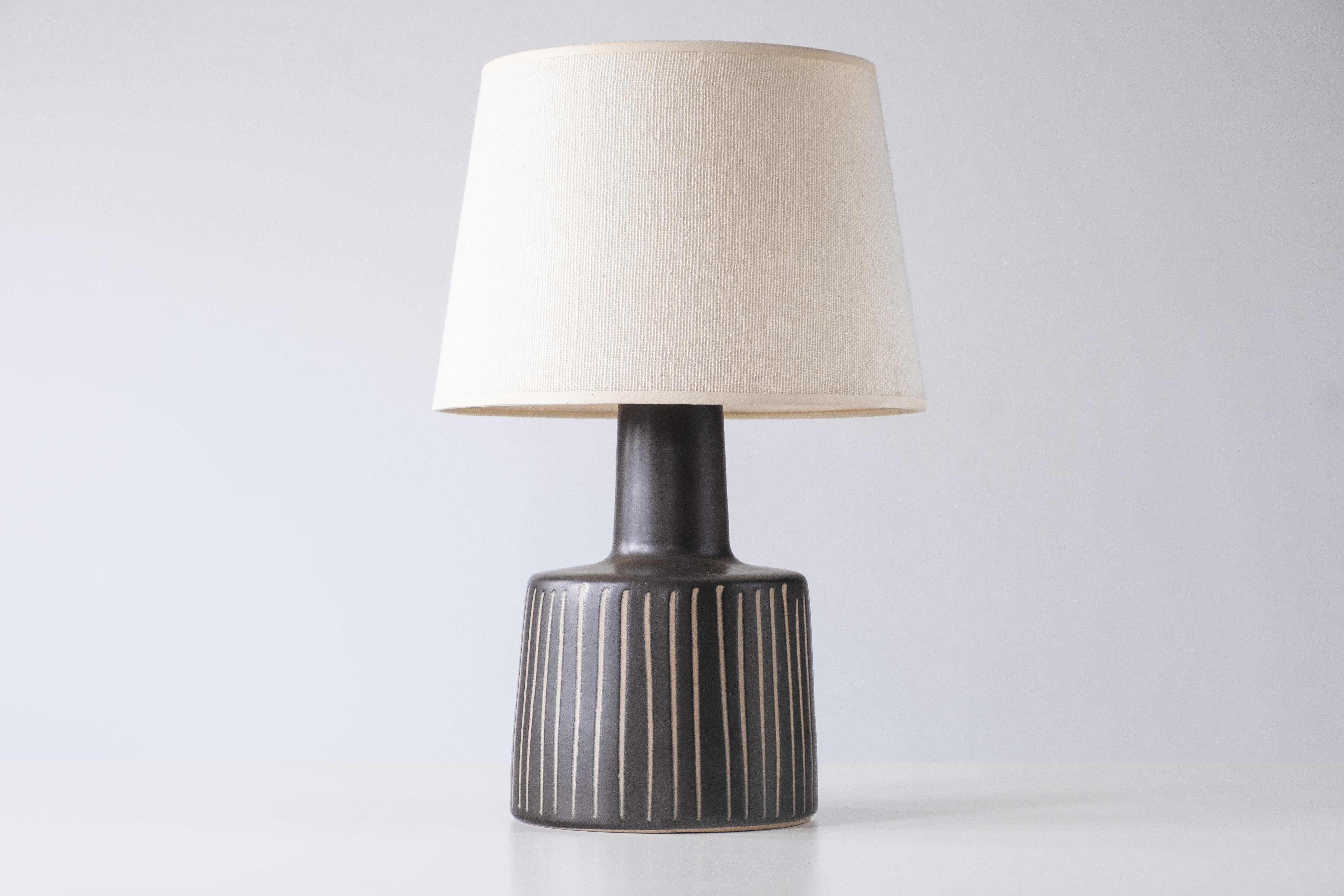 What is it?
—
Another gem from the masters of midcentury lightning – Gordon and Jane Martz.

This signed Martz model 105 lamp comes in a matte black / very dark gray glaze with a vertical stripe incised design. Technically this glaze is the Marshall