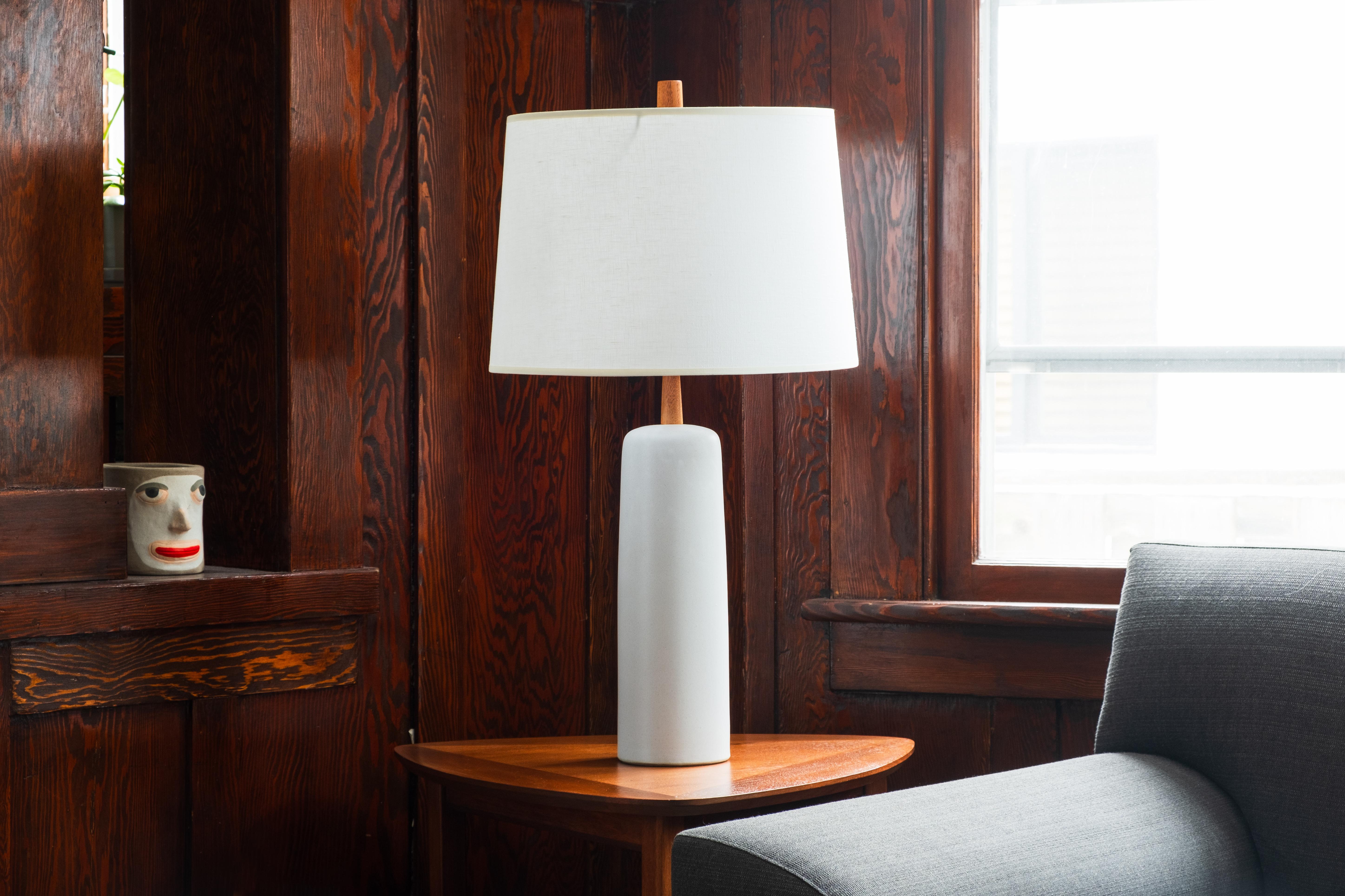 WHAT IS IT?
—
This signed Martz Model 41 lamp comes in a matte white / light gray glaze. The tall ceramic body gives way to a thin, tapered walnut neck and the whole ensemble is capped off with a reproduction Martz walnut finial.

This model of lamp