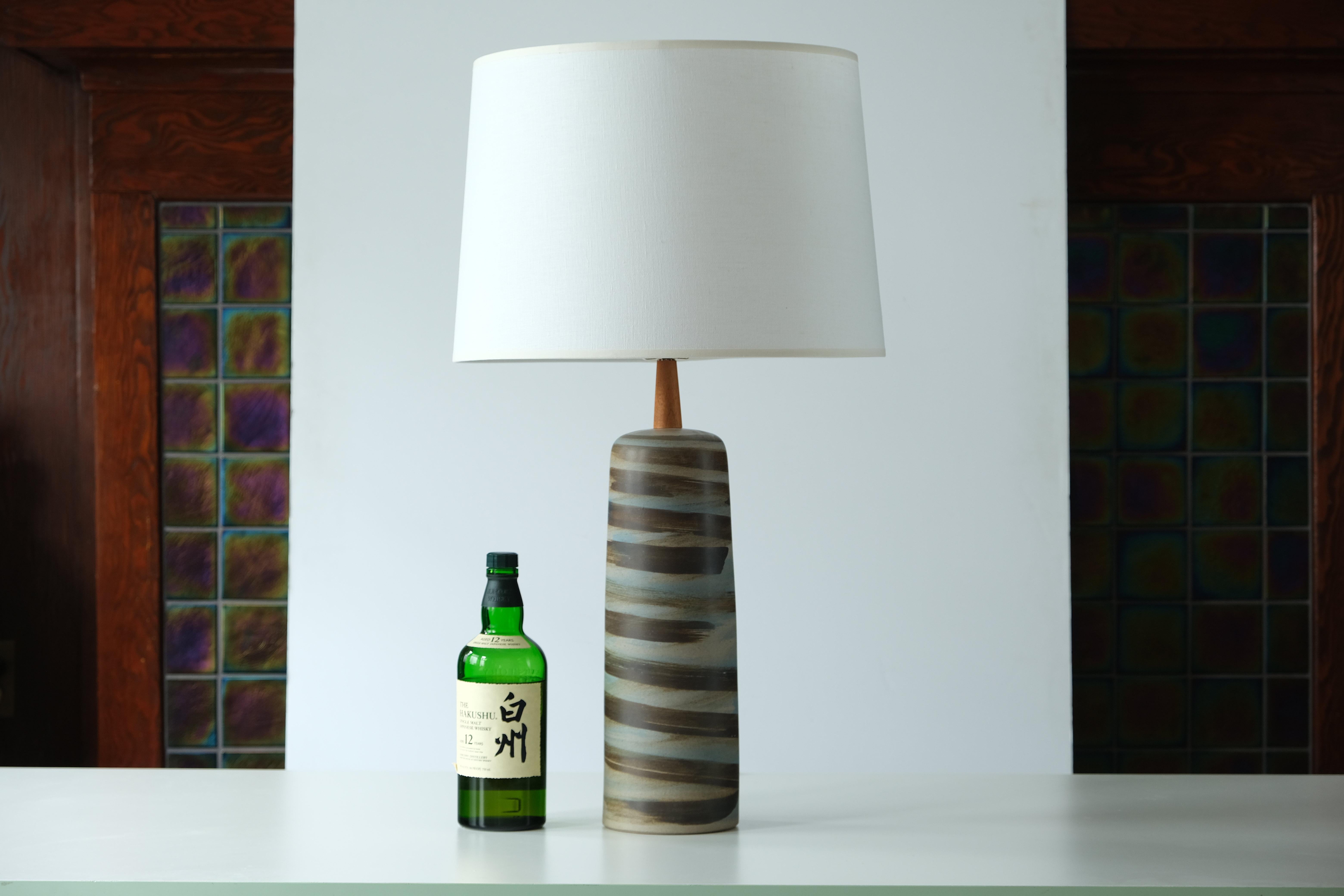 WHAT IS IT?
—
This signed Martz Model 41 lamp comes in a swirled brown and blue glaze. The tall ceramic body gives way to a thin, tapered walnut neck and the whole ensemble is capped off with a reproduction Martz walnut finial.

This model of lamp