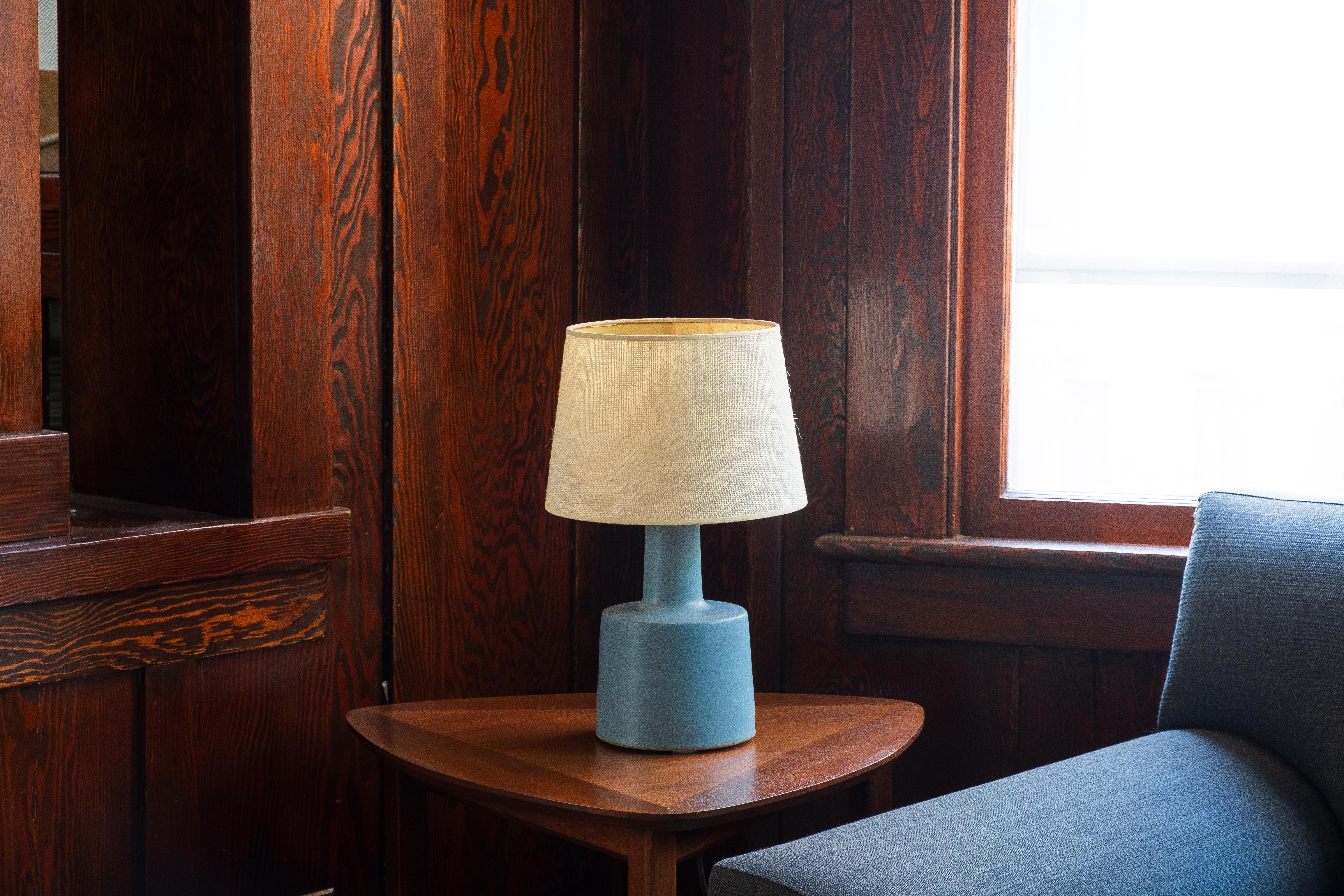 What is it?
—
These signed Martz model 105 lamps comes in a matte robin's egg blue glaze with darker flecks and specks of browns and black. They will arrive with a new set of burlap shades that exactly match the dimensions and construction of the
