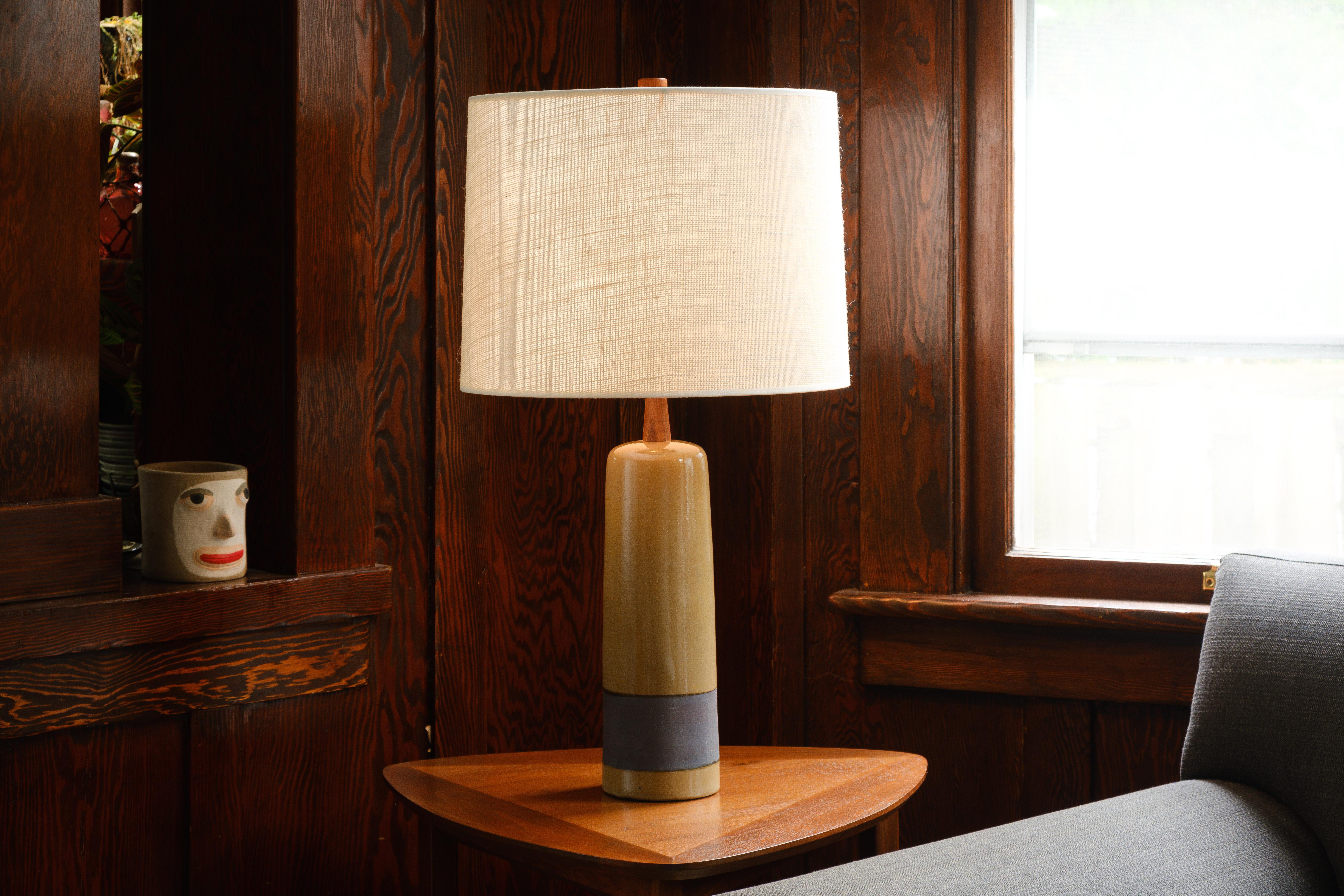 What is it?
—
Another gem from the masters of mid century lightning – Gordon and Jane Martz.

This signed Martz lamp comes in a glossy tan / yellow ochre glaze with an wide band of unglazed iron oxide that wash that forms a reddish purple stripe