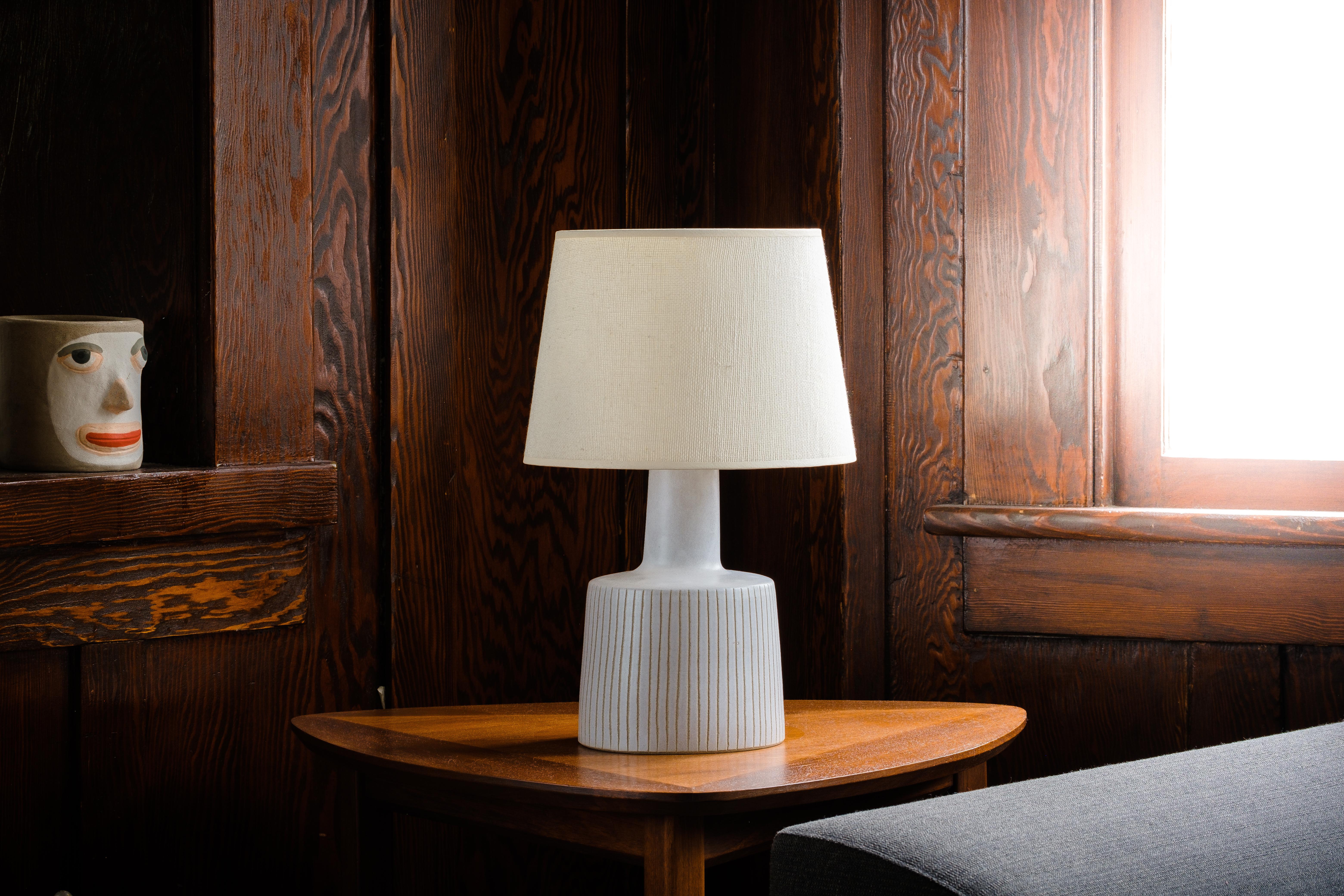 What is it?
—
Another gem from the masters of midcentury lightning – Gordon and Jane Martz.

This signed Martz model 105 lamp comes in a matte white glaze with a vertical stripe incised design. A simple, but very much sought after Martz