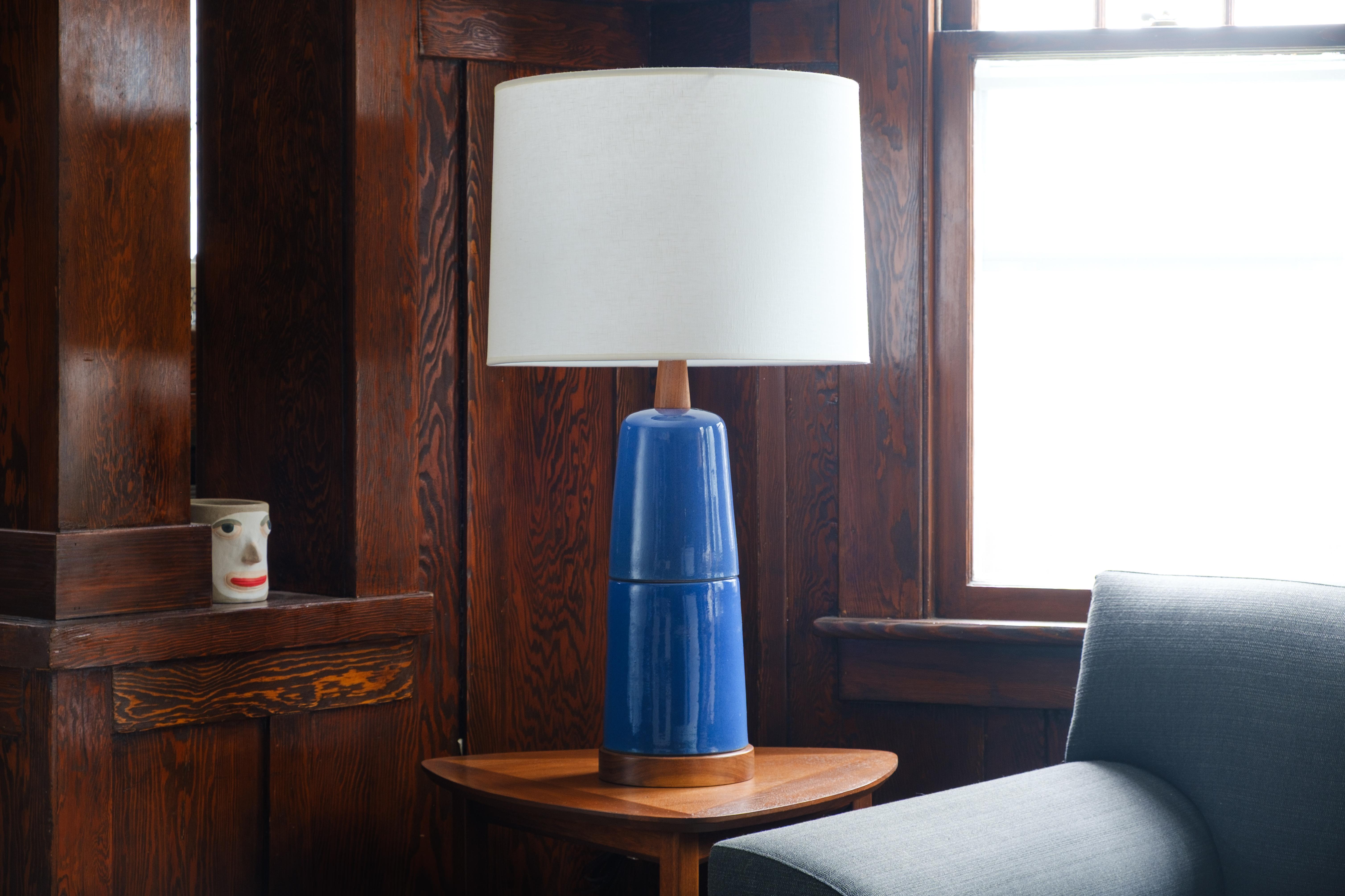 What is it?
—
This pair of Gordon and Jane Martz lamps features a glossy sapphire blue glaze with a speckled, mottled surface. Upon close inspection, the glaze reveals a subtle interplay of a core blue color and darker speckled dots, adding depth
