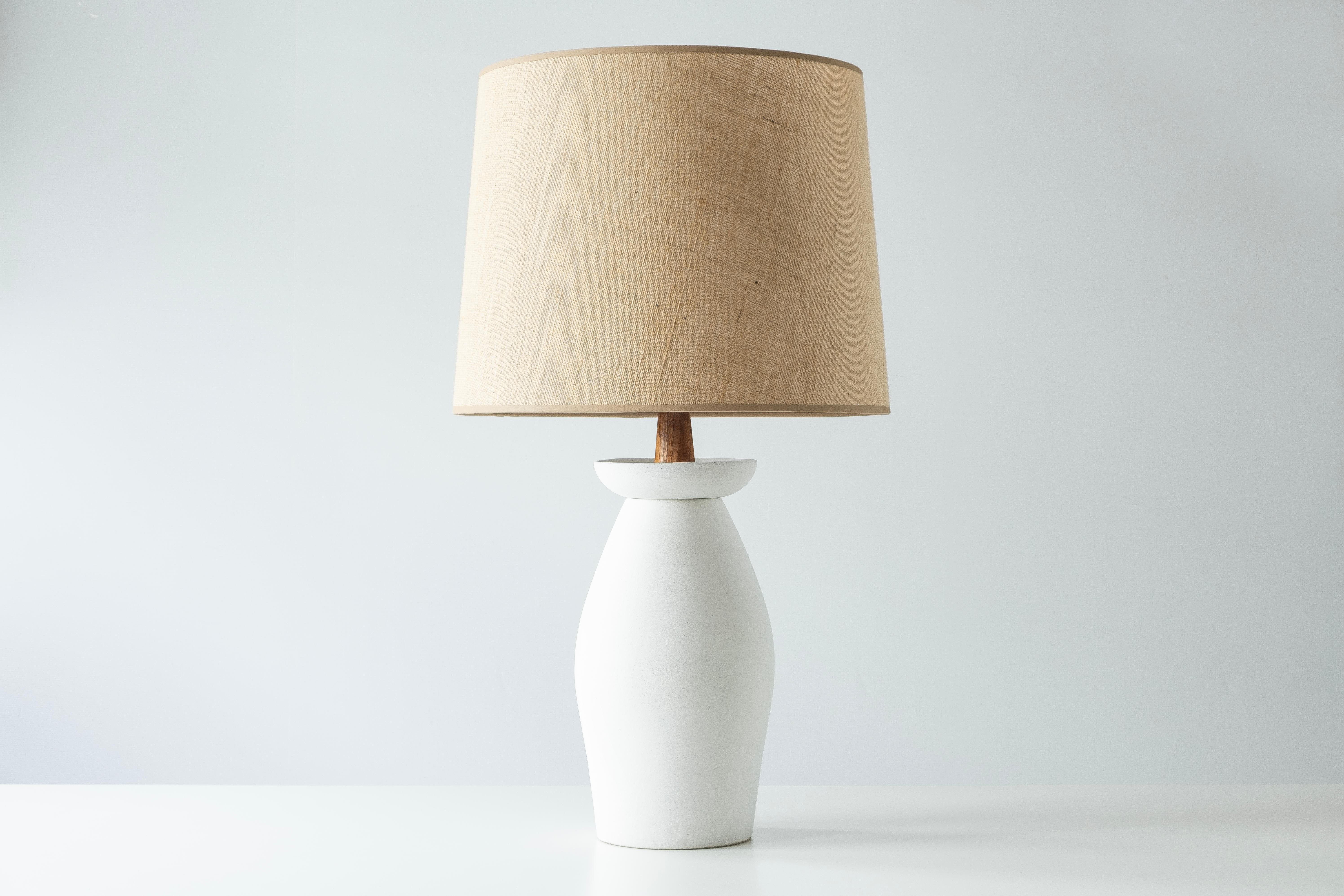 ?? What is it?
—
This signed Martz Model 167 lamp comes in a matte, unglazed white base. This model was slipcast then painted with a white slip, giving the lamp its bright white color. A rounded base is topped with an upturned collar that houses a