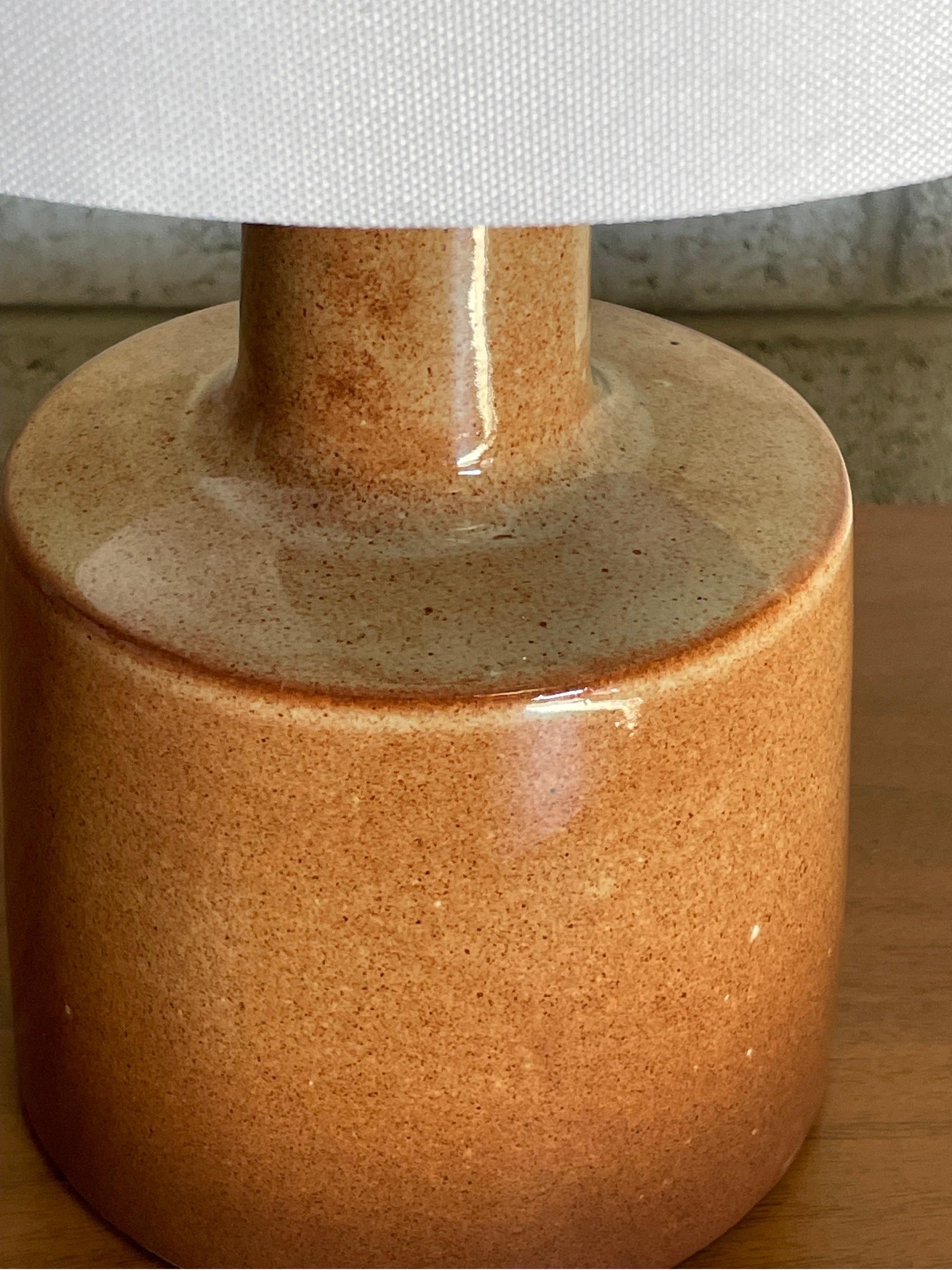Lampe de table conçue par le duo de céramistes Jane et Gordon Martz pour Marshall Studios. La couleur est une couleur inhabituelle semblable à la terre cuite avec un glaçage brillant. 

Dimensions générales : 
16