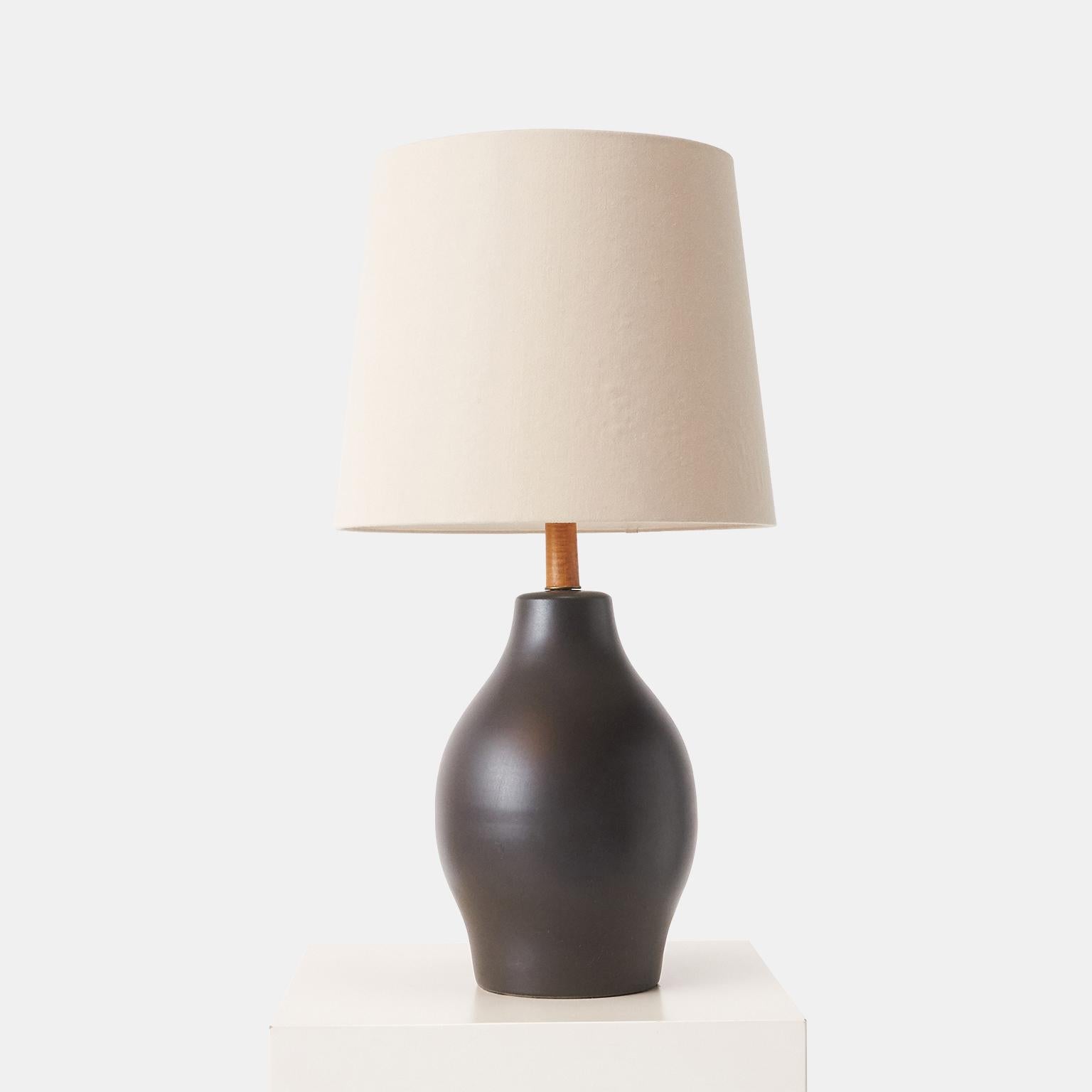 A matte dark brown table lamp by Jane and Gordon Martz for Marshall Studios. Stoneware base with teak neck and finial. Etched “Martz” on the back. Rewired.

Complete with a beautiful hand-crafted shade, in the original style and made from a