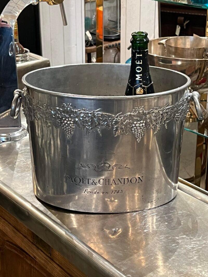 Midcentury (or possibly 1940s) oval pewter champagne cooler, with the most beautiful ornate outer, from France’s renowned Moët & Chandon.

It can hold 2-3 standard bottles of champagne and has an elegant appearance, with grape foliage garlands along