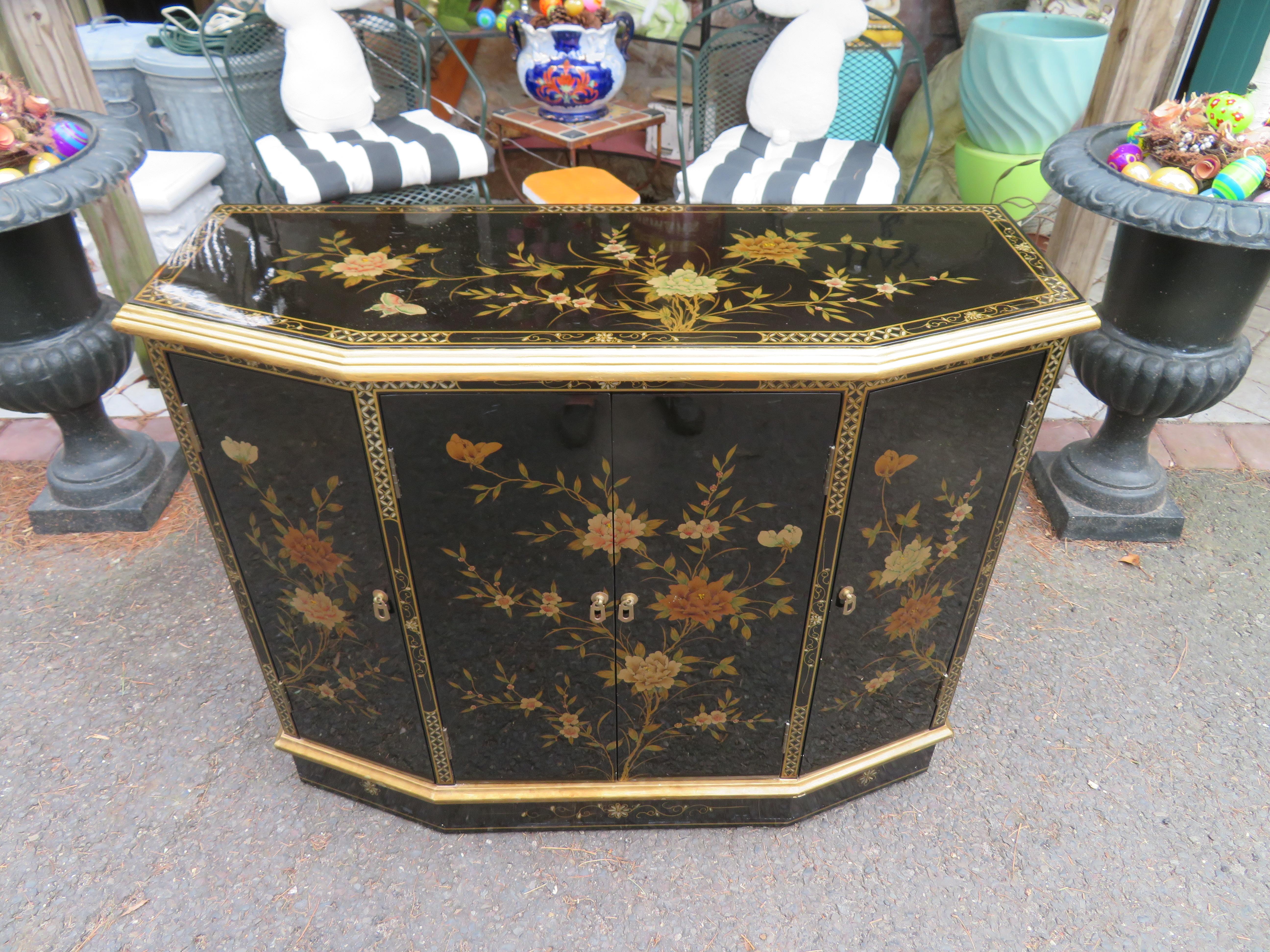 Marvelous Chinoiserie decorated black and gold console cabinet, Circa 60's. This lovely piece was well cared for and looks rarely used. The floral decoration is well-painted and is done on all sides including the back. It measures 32