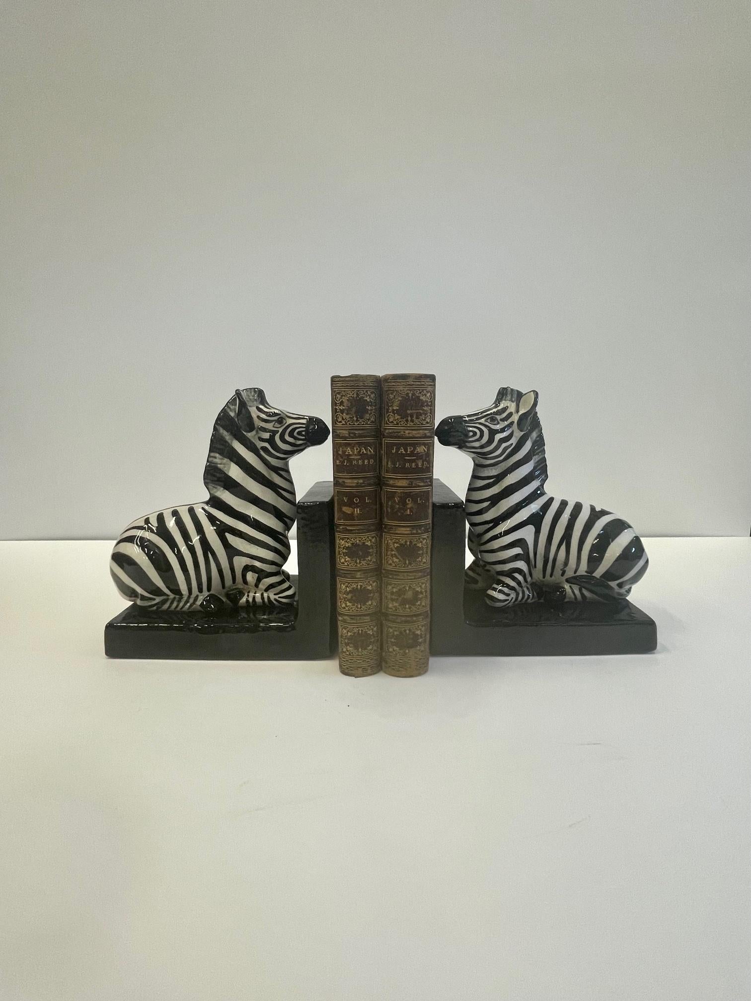 Chic pair of Italian glazed terracotta bookends having striking black and white zebras on black L shaped bases.