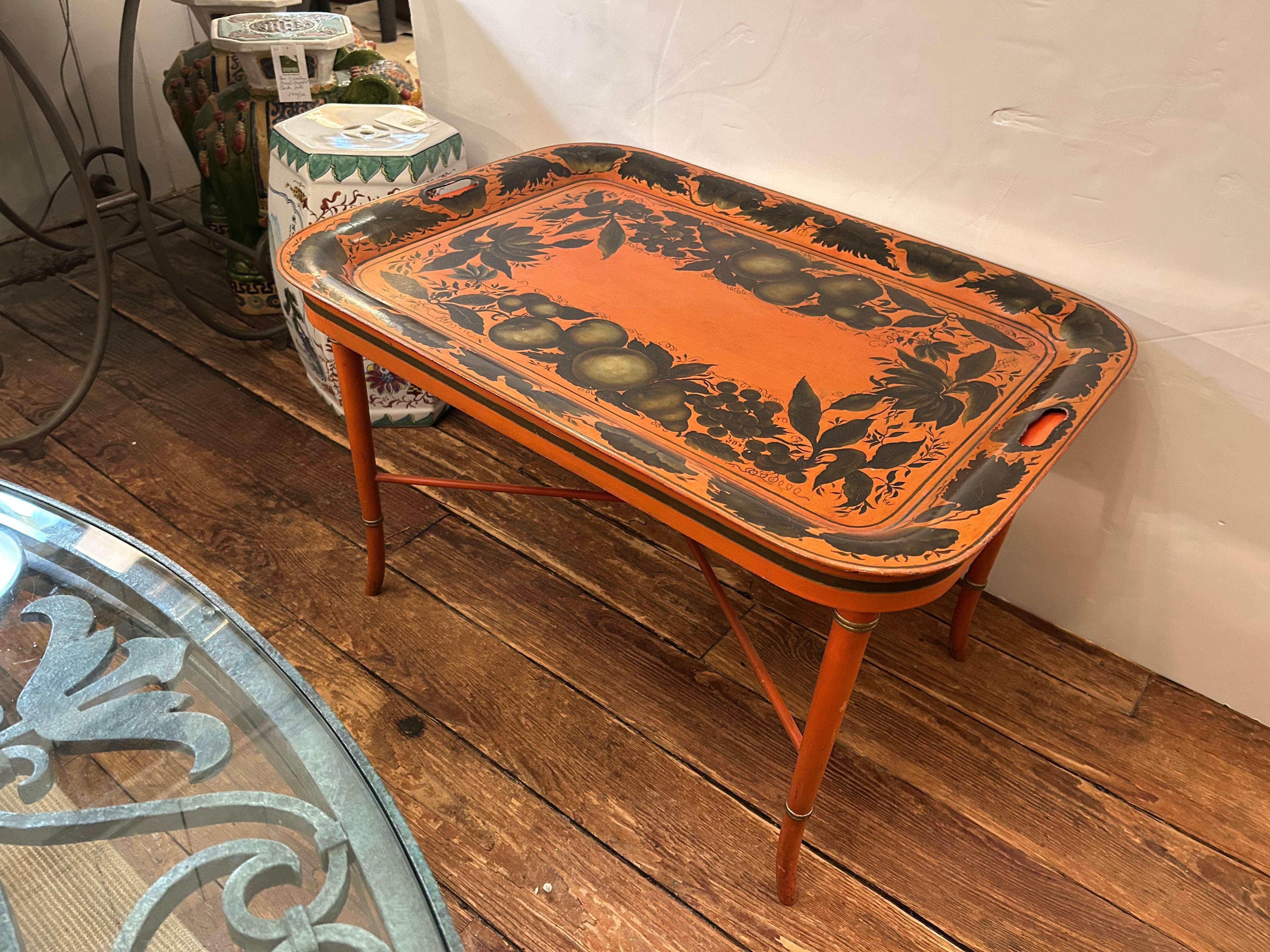 Wonderful vintage removeable tray top cocktail table in a fetching shade of orange with beautiful fruit decoration having elegant legs with gilded details.