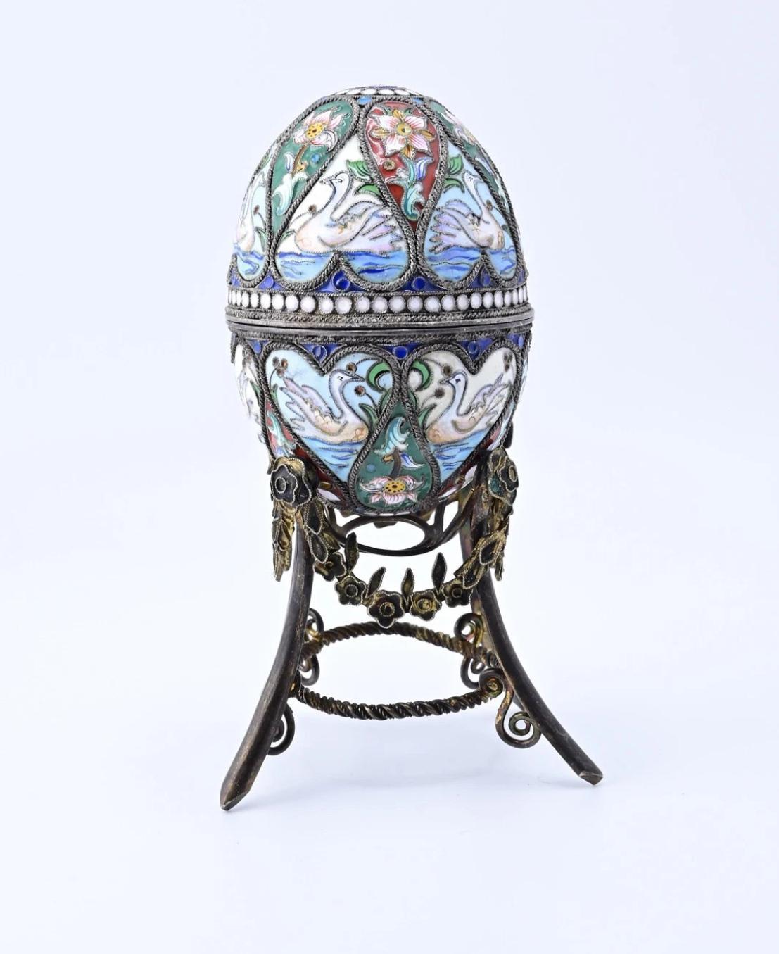 Te presentamos nuestro exquisito huevo decorativo ruso de plata esmaltada, una obra maestra de intrincado diseño y artesanía.

Esta cautivadora pieza muestra una superficie esmaltada meticulosamente, adornada con vibrantes dibujos de cisnes y