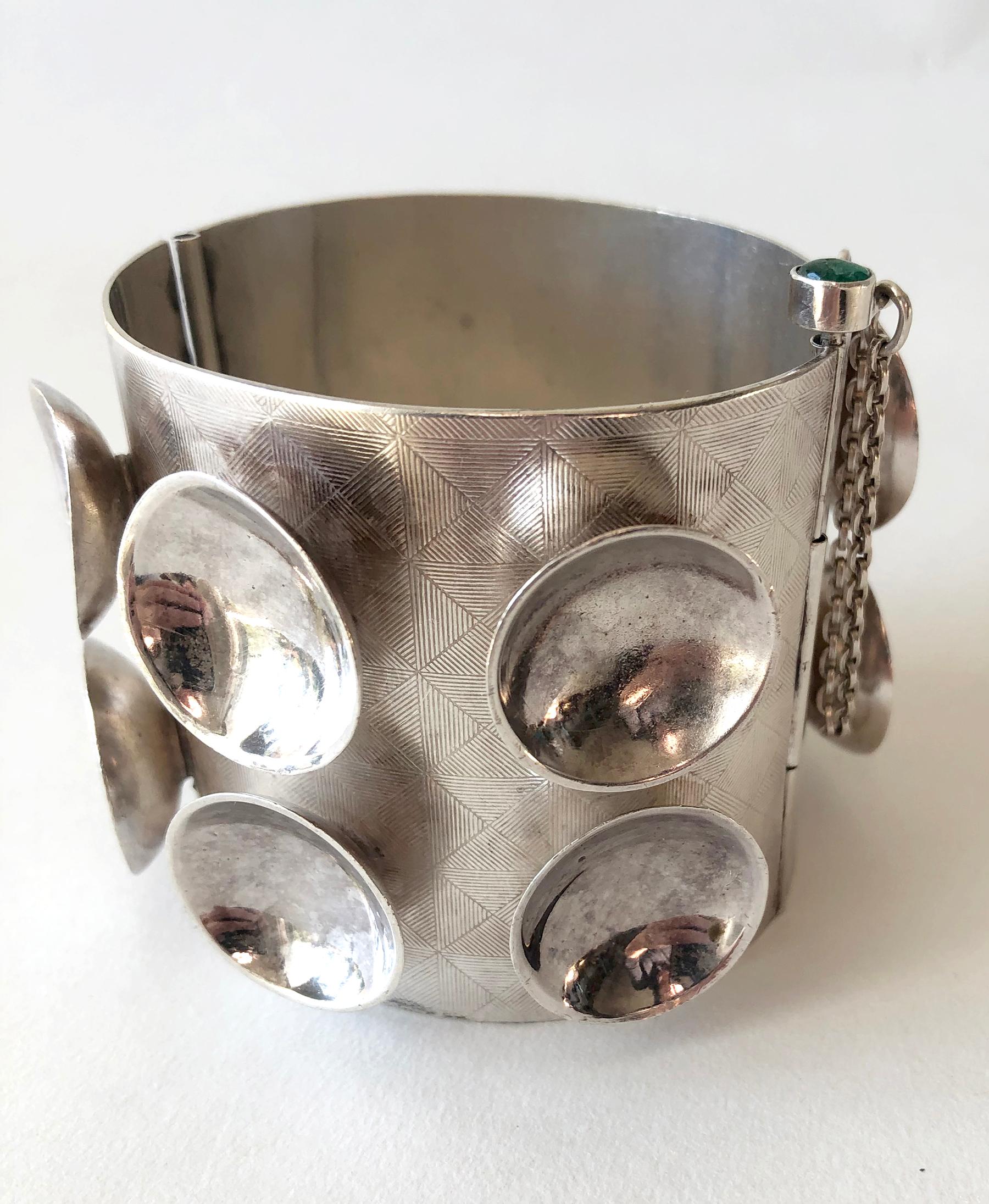 One of a kind sterling silver cuff bracelet decorated with concave cups and incised design by Mary Ann Scherr of North Carolina.  Bracelet fastens with a long pin, which is topped with an emerald cabochon.  Cuff is 2.25