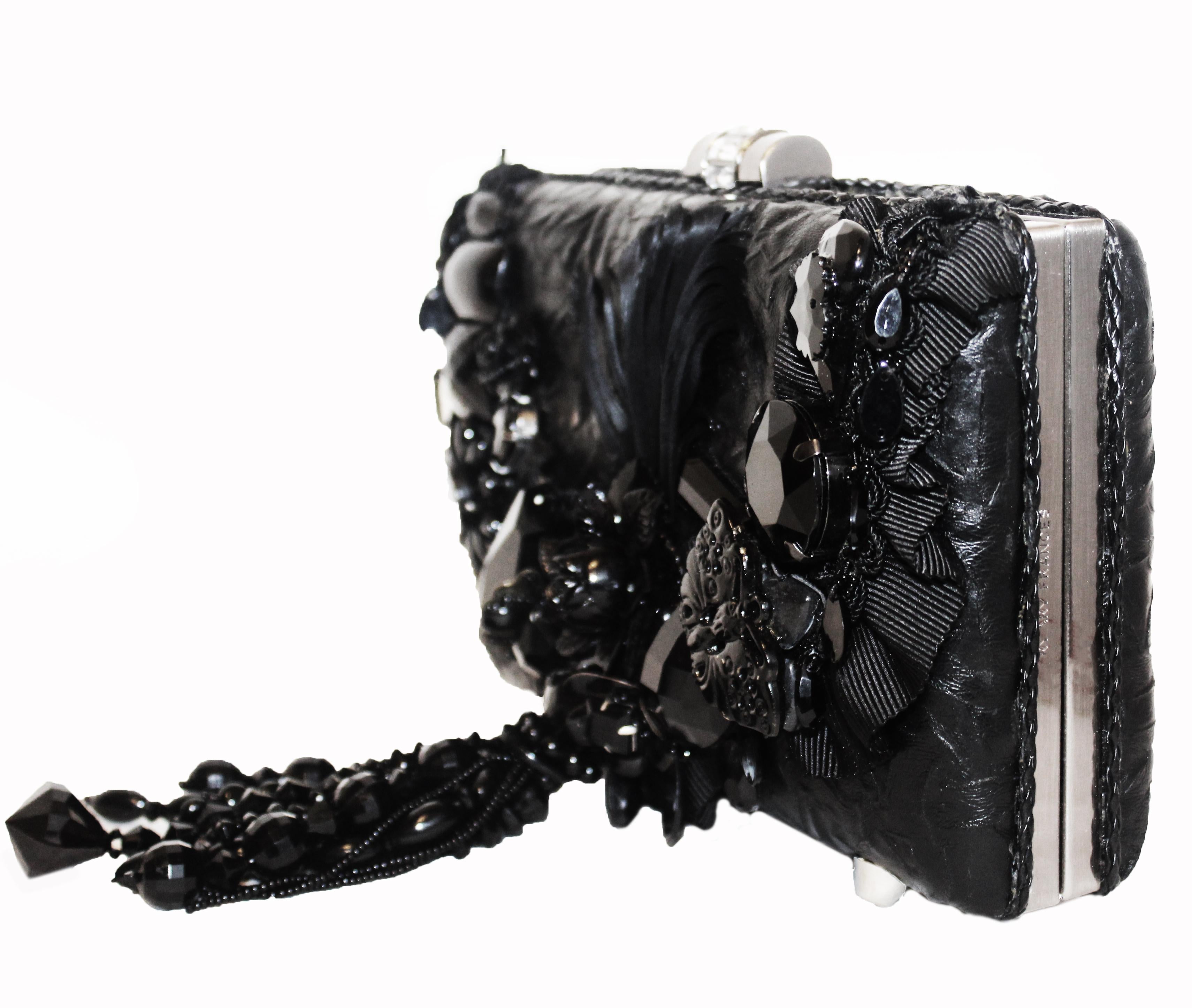 Mary Frances black heavily beaded clutch bag includes a detachable shoulder chain.  This structured leather bag decorated with large plastic, resin and metal ornaments of flowers and butterflies opens to a center compartment lined in black raw silk