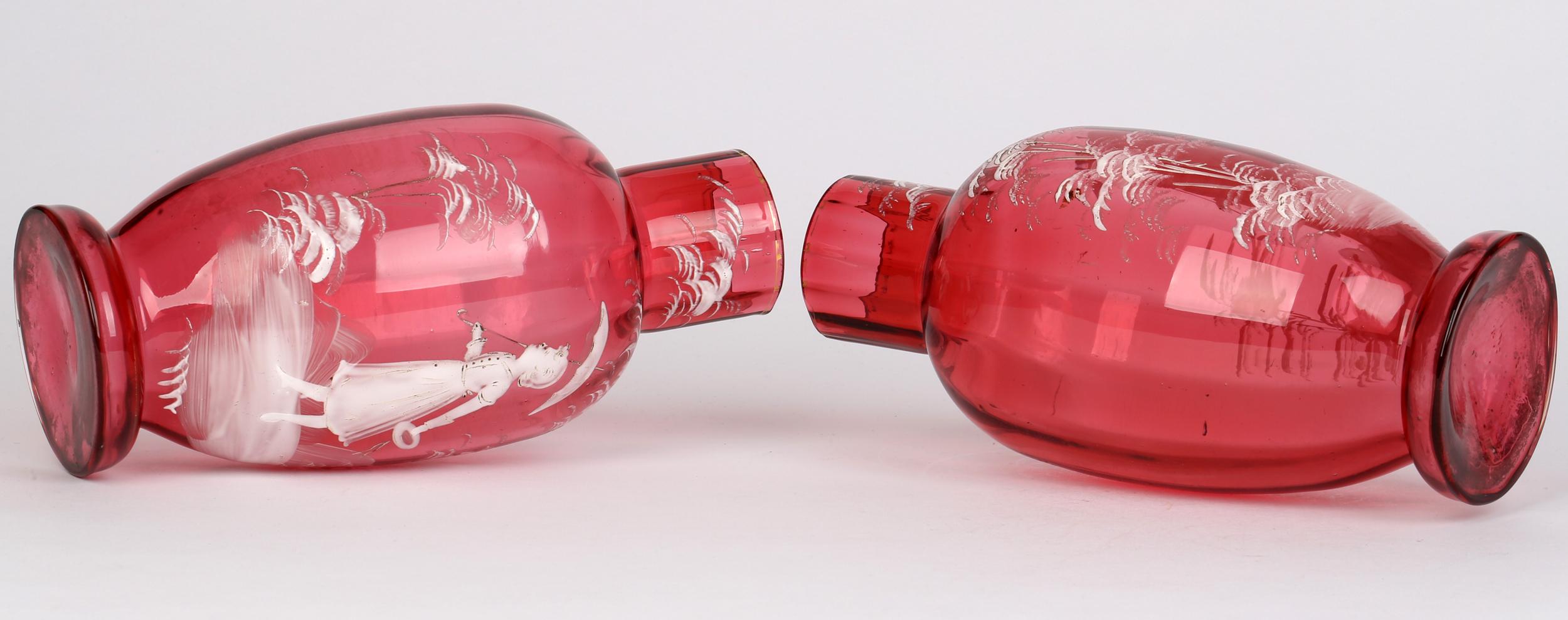 Stylish pair central European cranberry glass vases with girls with parasols dating from the 19th century. The blown glass vases have a slight ribbed design to the body with hollow blown bases and both are applied with girls holding hats and with