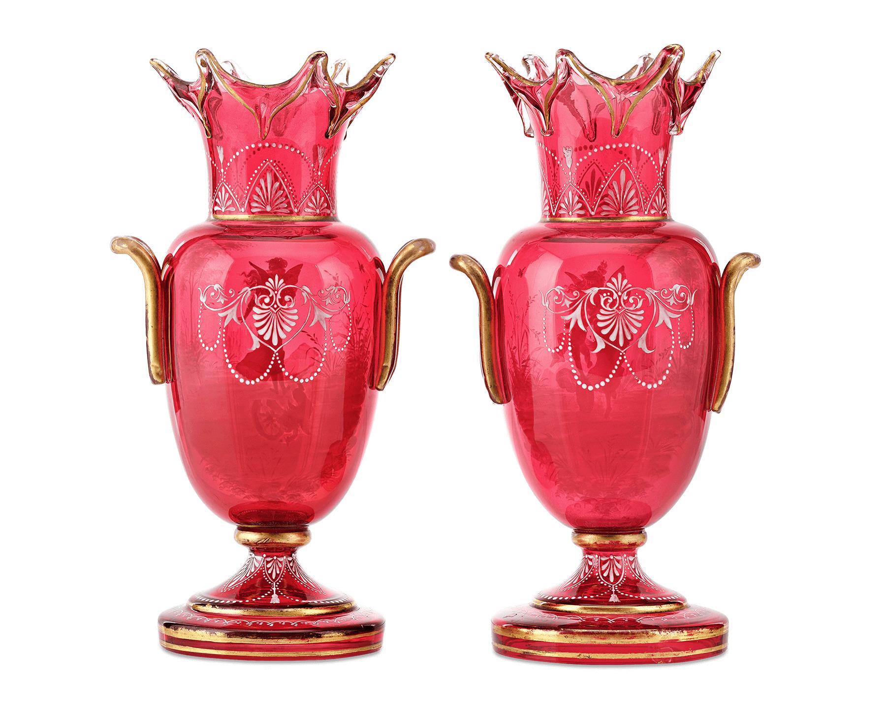 This beautiful and important pair of cranberry glass vases feature the timeless childhood silhouettes known as Mary Gregory. The motifs are executed in white enameling of varying thickness to give the images amazing depth. This elegant pair is a