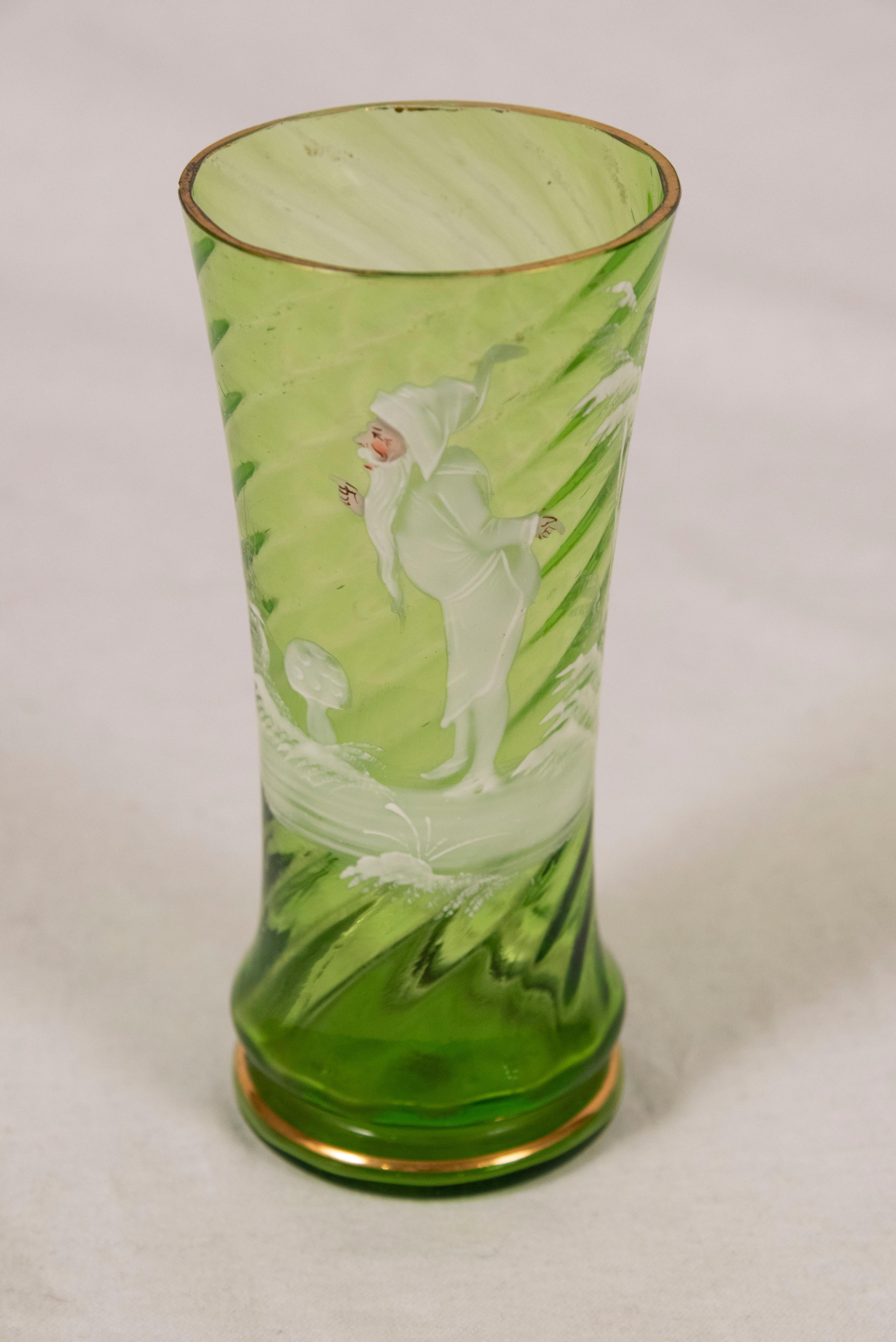 Mary Gregory (American) Green glass five-piece lemonade set comprising a swirled pitcher with flared mouth and applied handle, and four matching tumblers, each decorated with a gnome figure amongst mushrooms in a wintery wooded landscape.