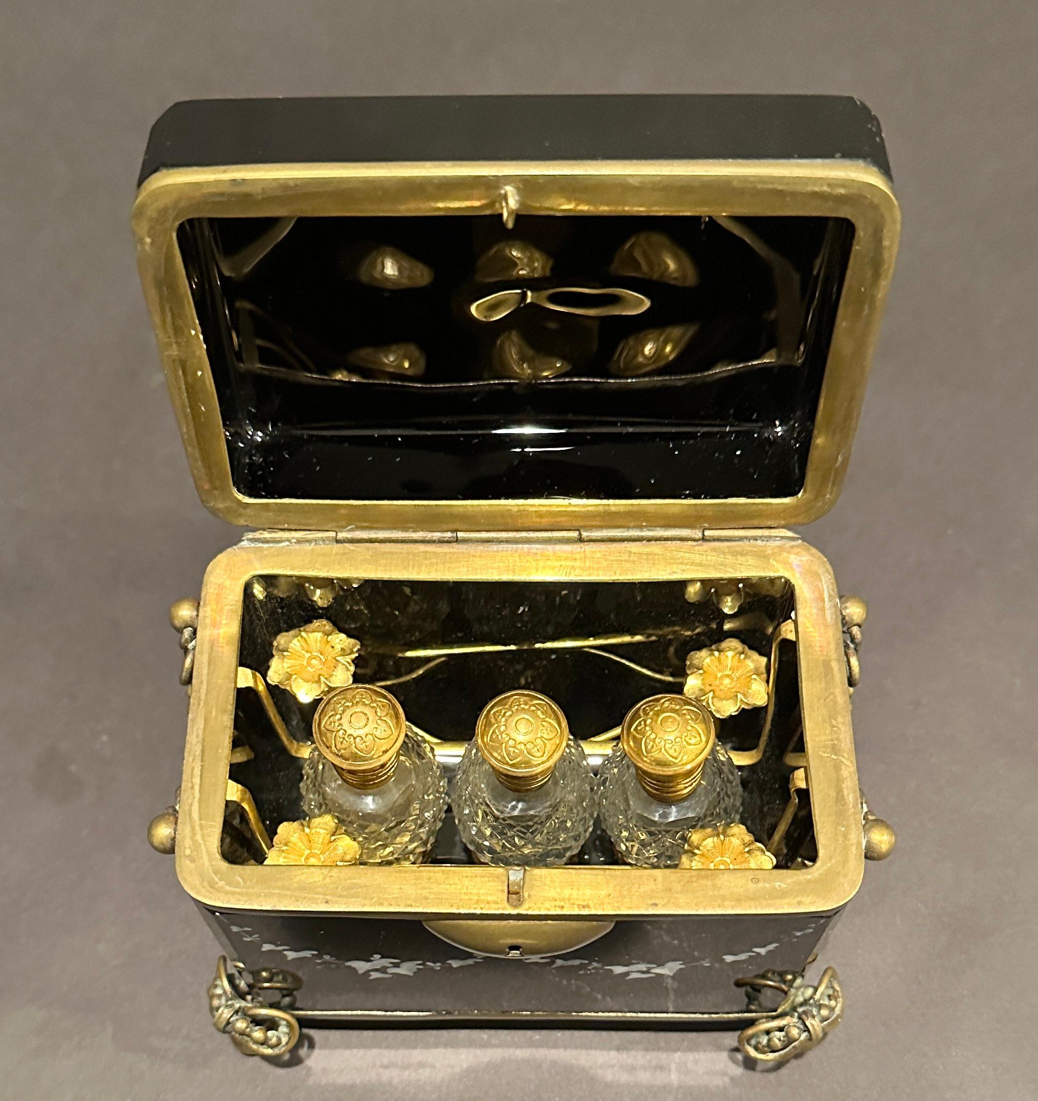 Exquisite piece of Mary Gregory  all original black amethyst glass hinged perfume box. Inside is formed with gilt wire inserts with  three glass scent or cut glass perfume bottles complete with glass stoppers. White painted enamel details of a