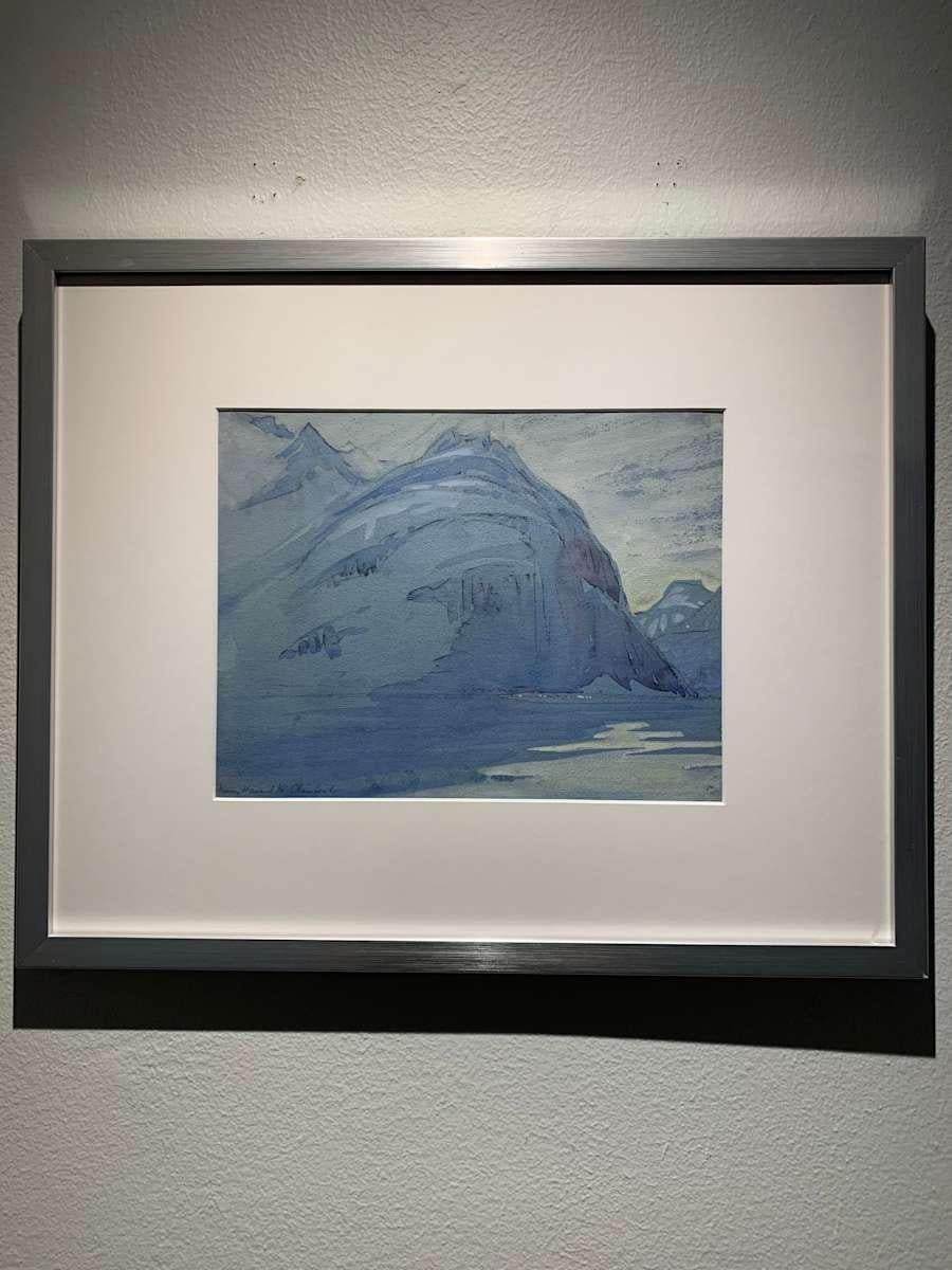This 17.38" x 21.38" watercolor painting by Mary Howard represents a snow capped mountain and waterscape. Howard utilizes a limited color palette of only blues, creating a unified composition. The mountain takes up the majority of the composition