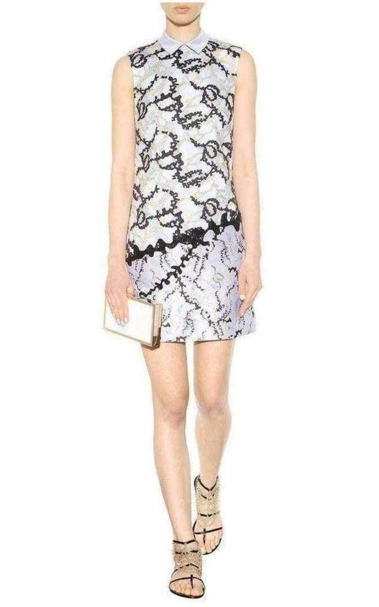 A modern update of the classic shirt dress, the Conquer Dress is created from oxford blue cotton poplin embroidered with foliage lace
The skirt is adorned with black bugle bead embellishment on a base of color-blocked foliage jacquard to create an