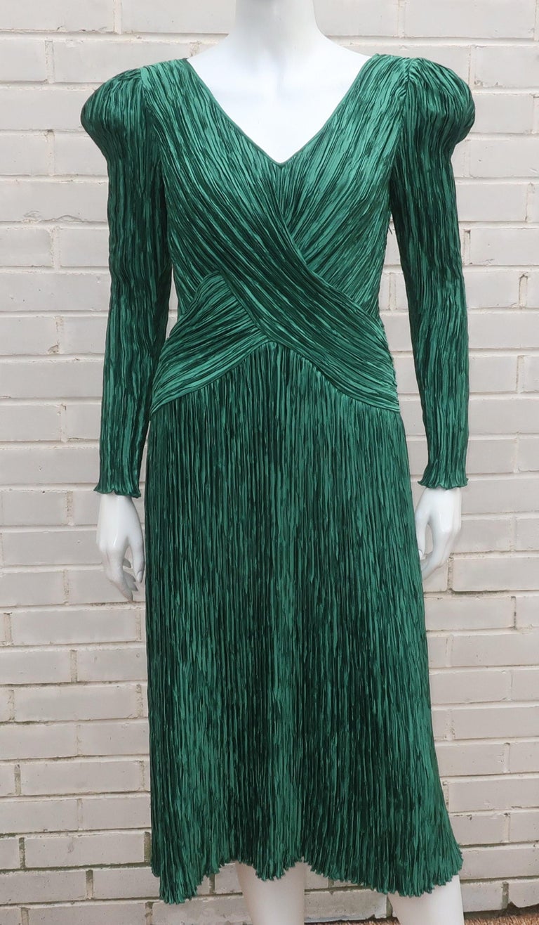 Early 1980's Mary McFadden cocktail dress in a rich emerald green color with McFadden's signature exotic style and micro pleated fabric similar to the designs of Mario Fortuny.  The dress has a hidden zipper on the side with a criss cross bodice and