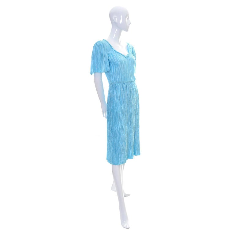 This is a vintage Mary McFadden Couture dress in a beautiful shade of blue. This  pretty vintage fortuny style pleated dress has butterfly sleeves, a fitted waist, and  a pretty neckline trimmed with a soft ruffle.  This dress is labeled a size 4,