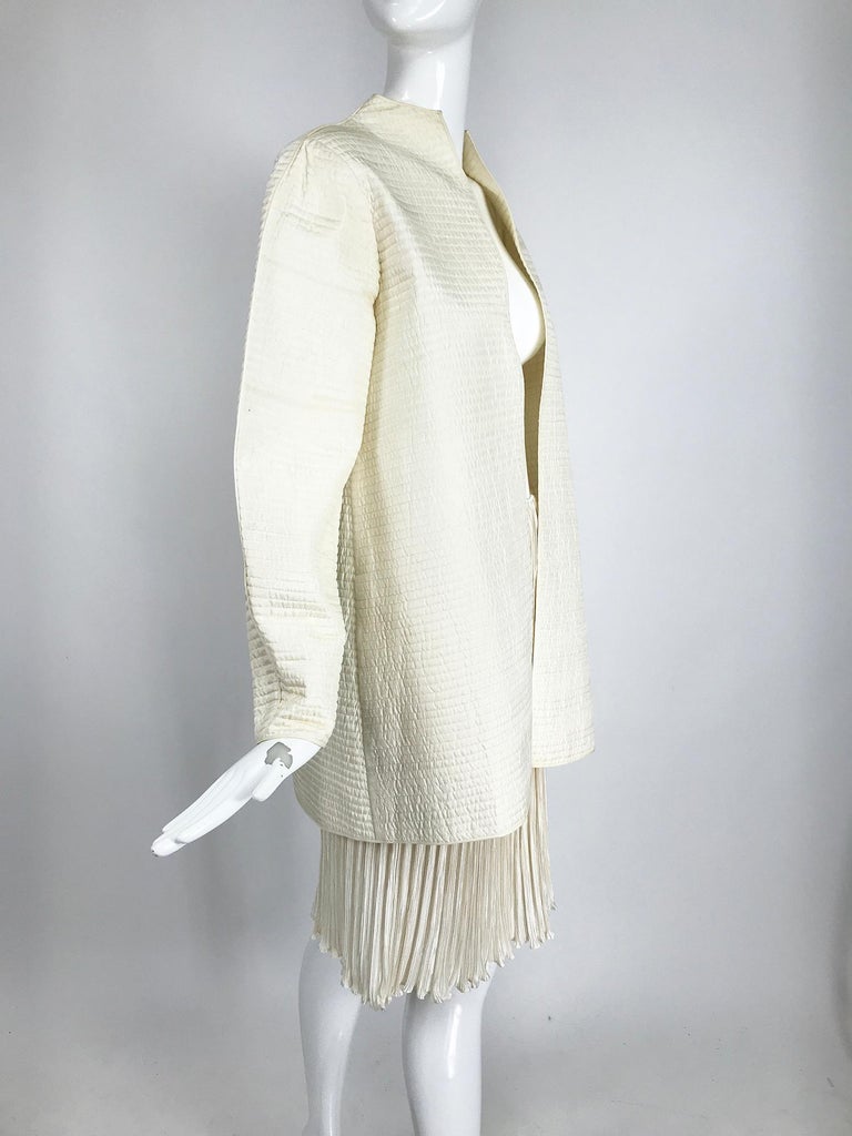 Mary McFadden Ivory quilted jacket and matching Fortuny style pleated short skirt set. This beautiful set is perfect for any special occasion and would even make a stunning wedding outfit.
The open front jacket has a high stand away neckline, a
