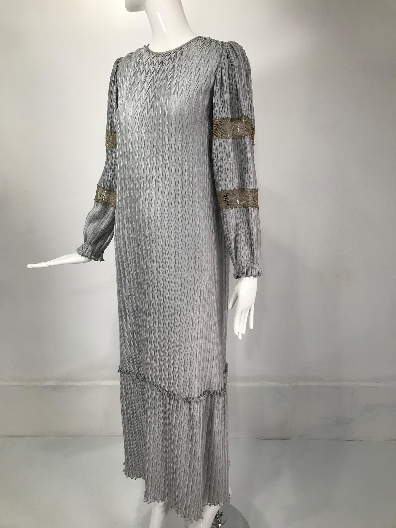 Mary McFadden silver grey & gold lace Collection 1 peasant style dress. Unusual chevron pleat design. Pull on dress with a jewel neckline, the neck band has ties in the back. Long sleeves with gold lace set in bands at the upper and lower arms, the