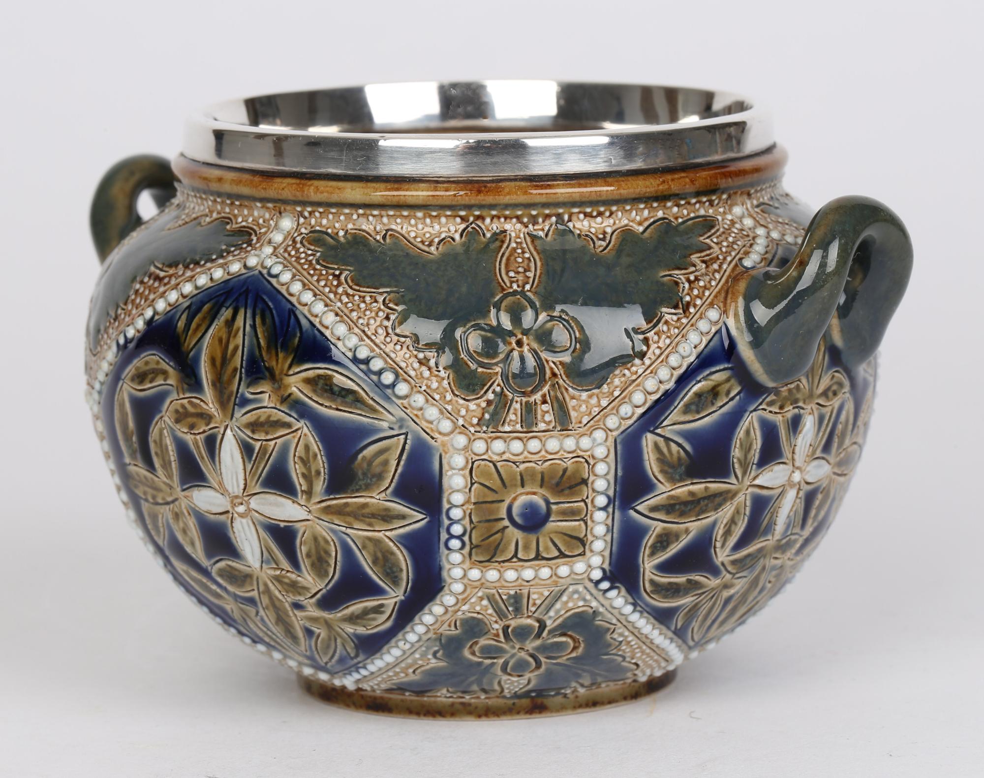 A stylish Doulton Lambeth Aesthetic movement stoneware silver mounted twin handled sugar bowl decorated with stylized foliage by Mary Mitchell and assisted by Ellen B Smith and Mary Aitken dated 1878. The rounded sugar bowl stands on a flat narrow