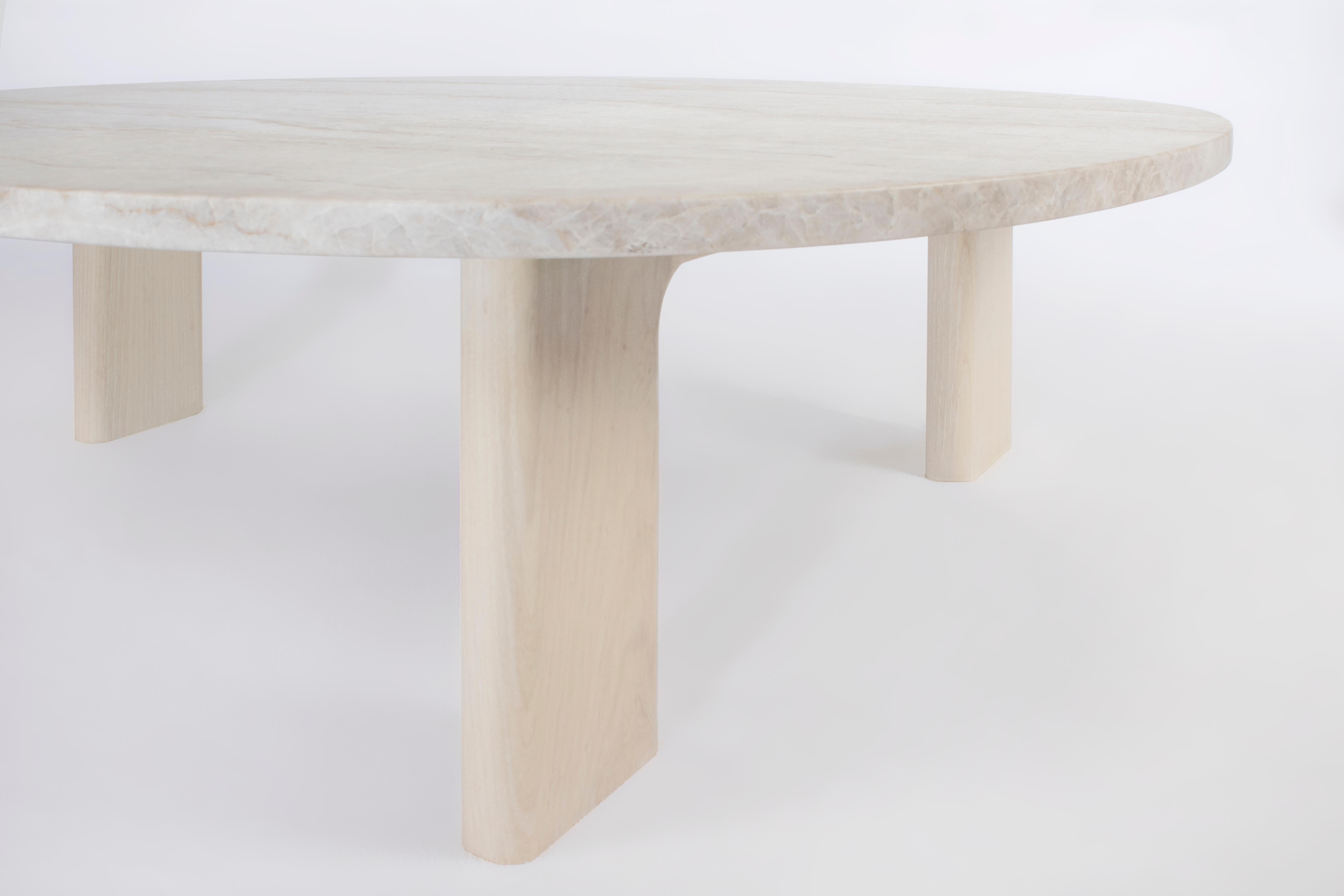 Der Vesta-Tisch schafft den Spagat zwischen Komfort und Raffinesse. Eine organisch geschwungene Marmorplatte ruht auf drei massiven, aber geformten Holzbeinen, die das entspannte Gefühl von Massivholz mit einer kühlen, raffinierten Marmoroberfläche