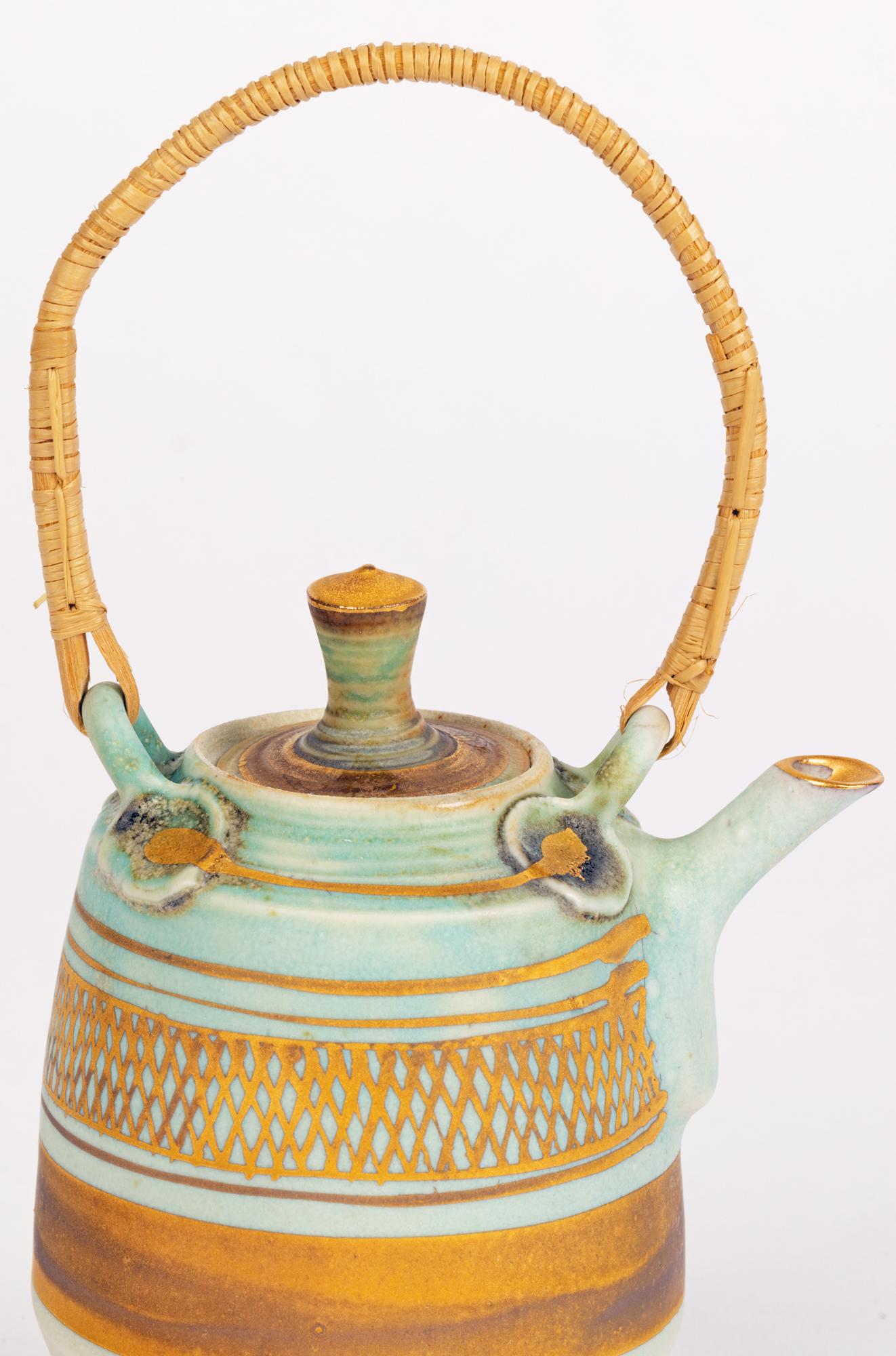 A stylish studio pottery porcelain miniature teapot with Islamic influence design in rich gilding on a green coloured ground by renowned potter Mary Rich (b.1940) and dating from the 20th Century. The small barrel shaped teapot has a short raised