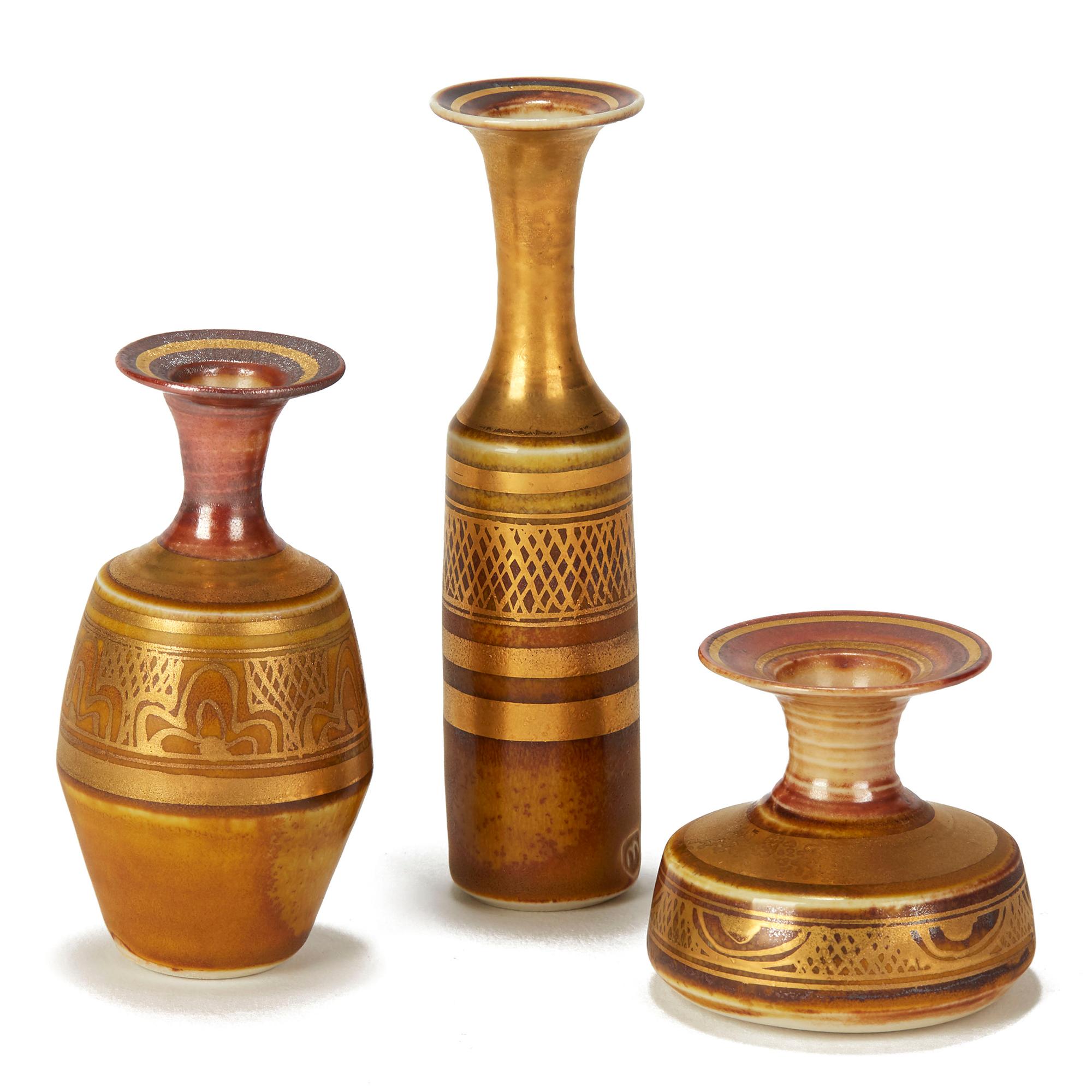 A collection of three miniature porcelain vases by Mary Rich (b.1940) of varying shape from tall slender form to squat rounded form each decorated with geometric and Islamic styled designs in red brown colours overlaid with rich gold lustre designs.