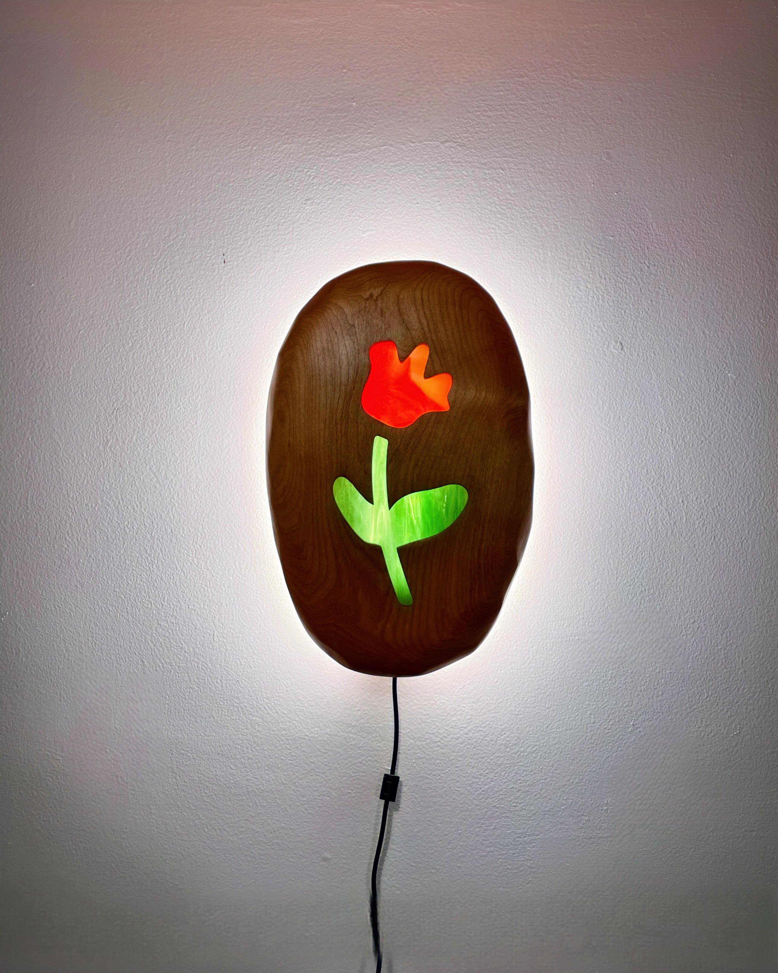 Routed and hand carved wall sconce, backlit in warm white LEDs, and controlled with a remote. Stained glass inlaid tulips come in a variety of colors. these medallions are inspired by vintage lighting from the studios favorite dive bar.