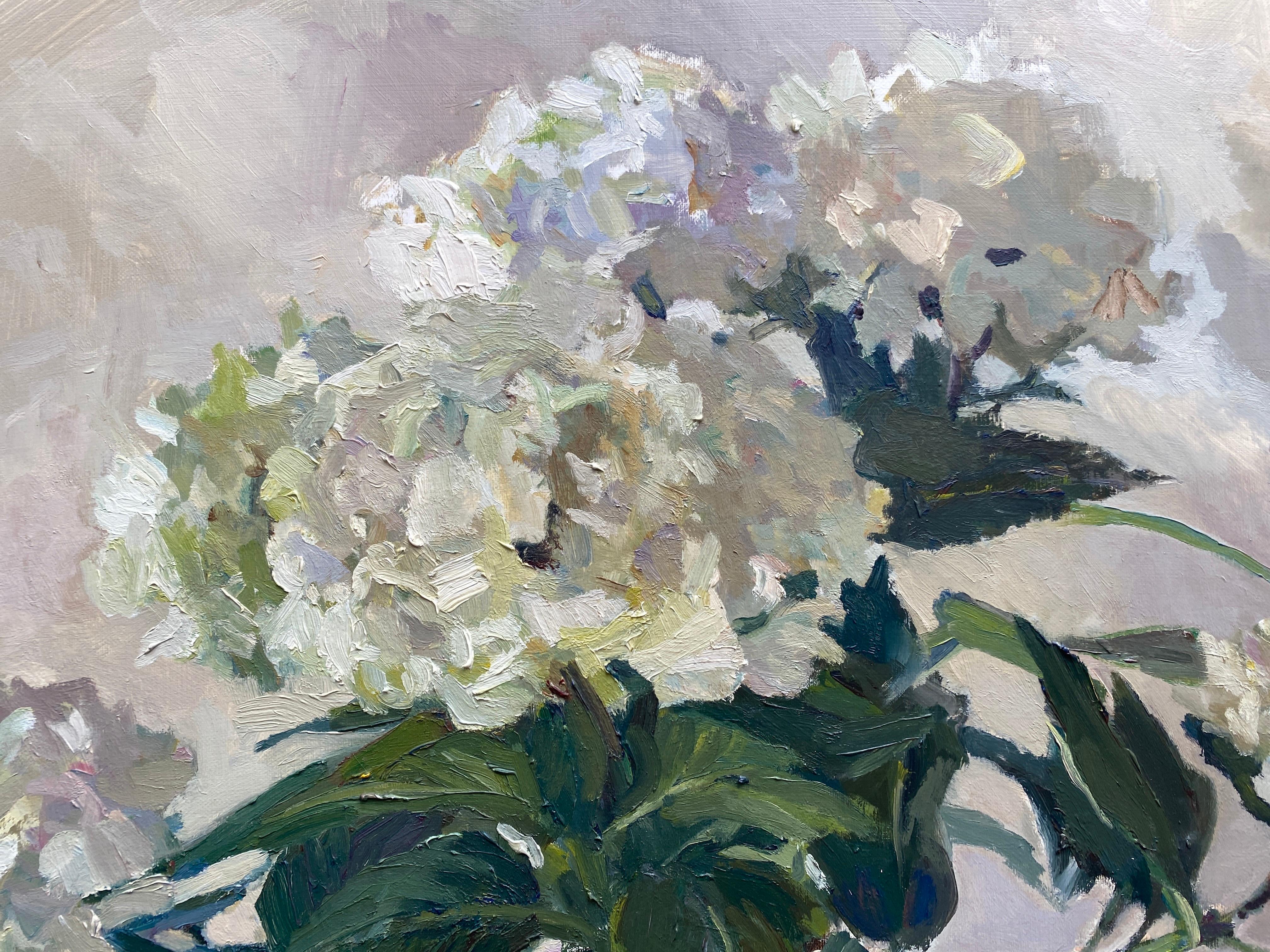 An oil painting of white hydrangeas blossoming upward from a round pot. Maryann Lucas finds the many colors in white, both in the flower petals and in the surrounding environment. Light and shadow play off the flowers, revealing rich tones of lilacs