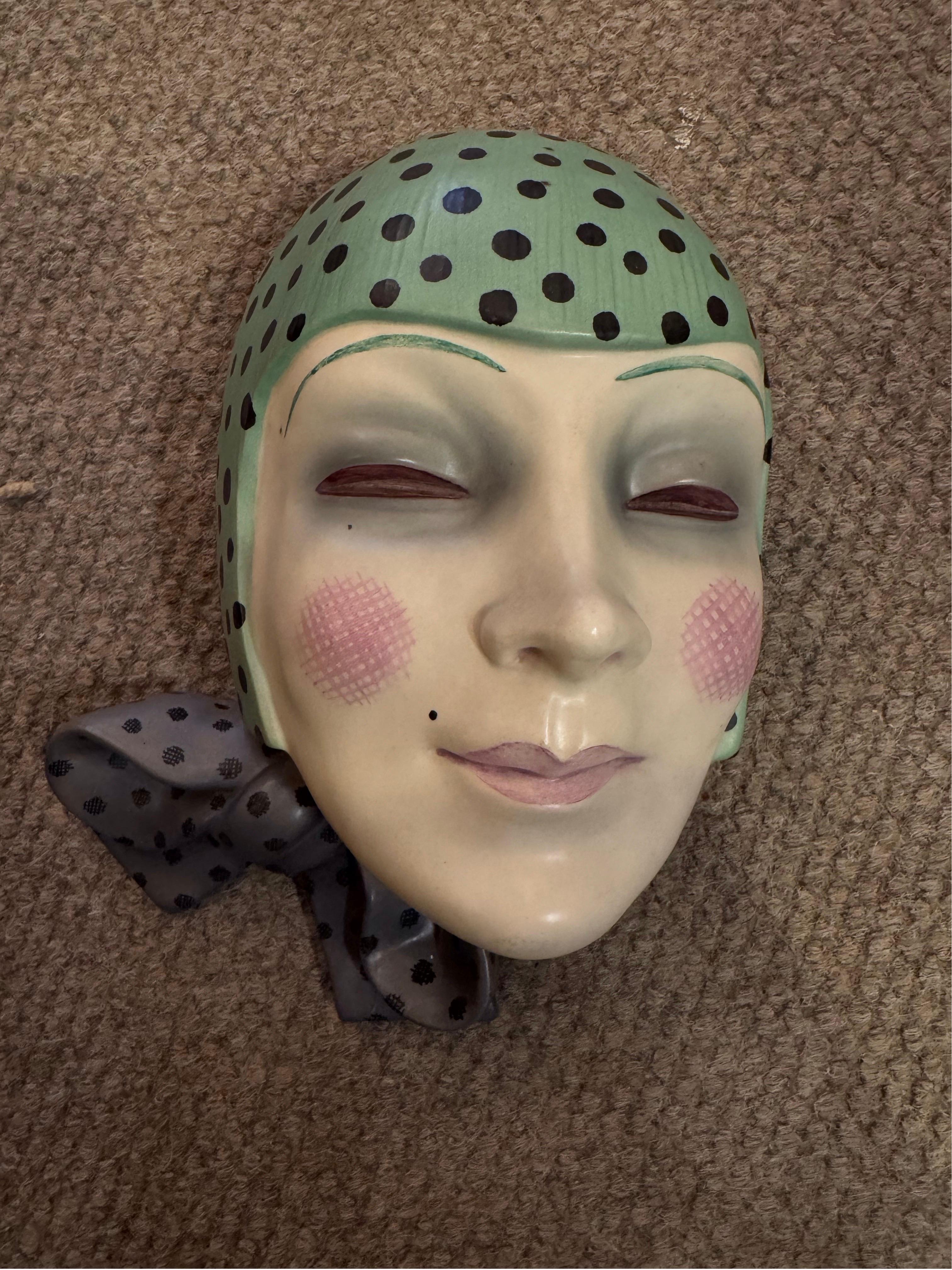 Dies ist ein seltenes und sehr begehrtes Modell. Die stilvolle junge Frau trägt einen grünen gepunkteten Schal und einen weiteren um ihren Hals. Ihre Lippen und Wangen sind mit Rouge betupft, sie hat einen Schönheitsfleck und schwülstig schattierte