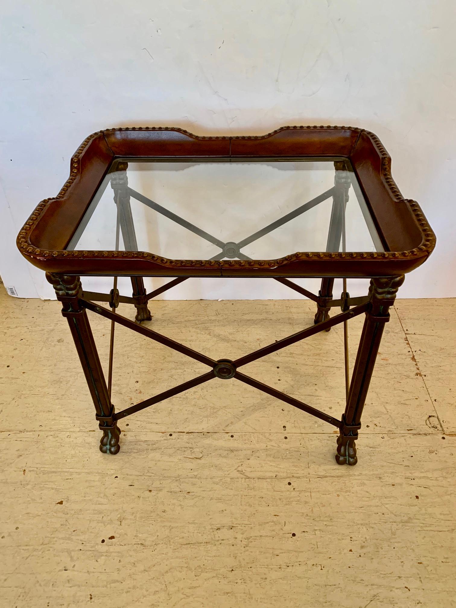 Handsome rectangular side or end table having tray shaped glass top with rich leather wrapped gallery finished with brass nailheads. The permanent top rests on iron campaign style base with stylish X's having central medallions.
Height of glass